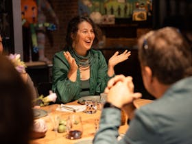 a woman happily gesticulates at a dining table