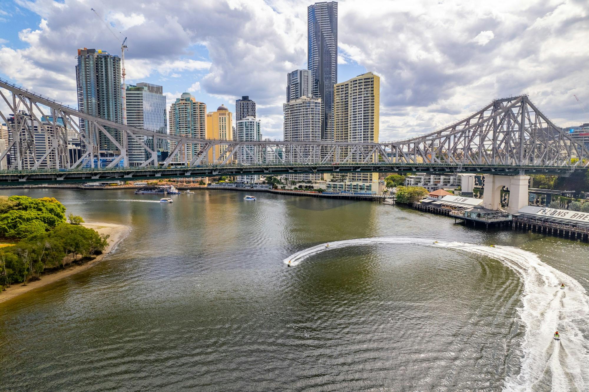 Aerial view of jet skis circling in front of Howard Smith Wharves as a group with Story Bridge