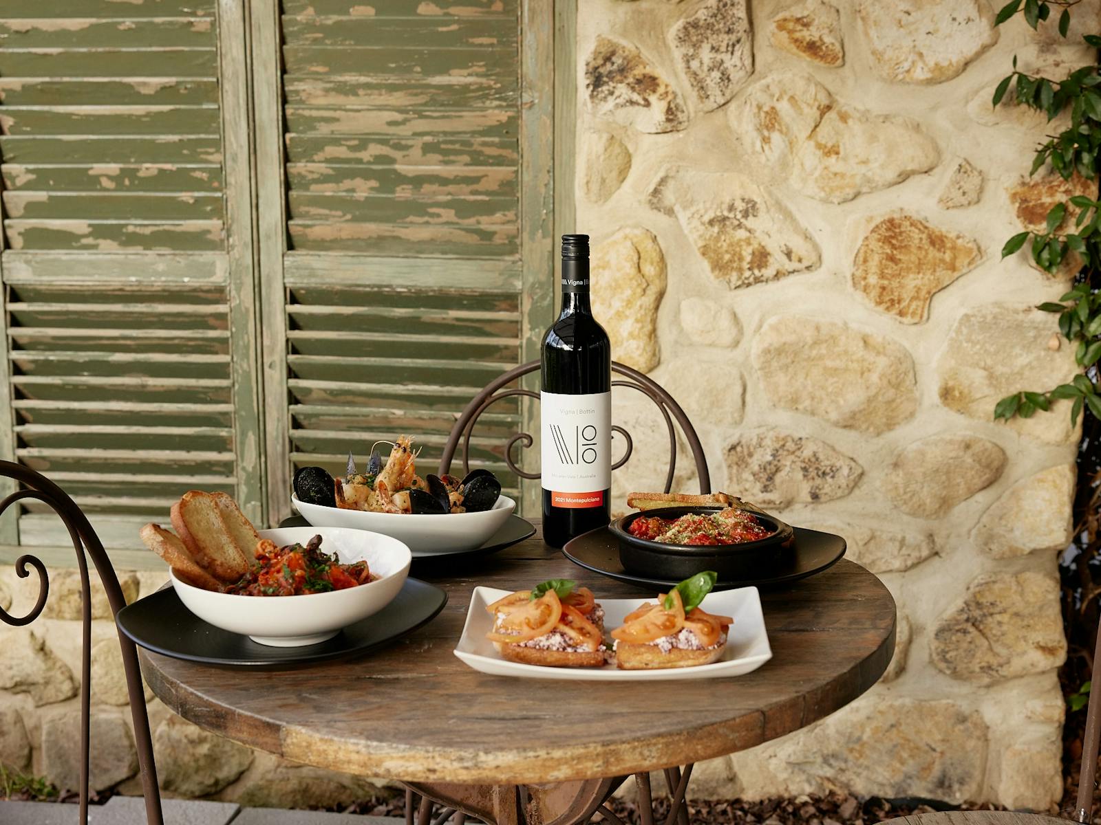 Image of various food and wine in front of stone wall