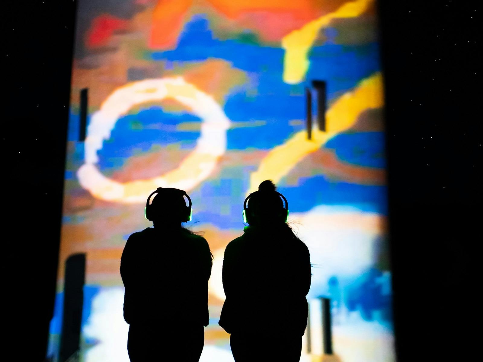 Two people in winter woolies, enjoying the light projection on Table Cape Lighthouse