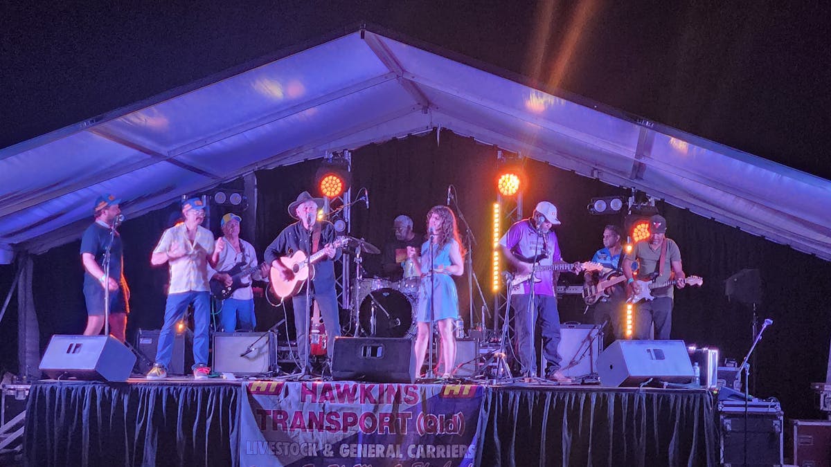 Singers supported by band on stage at outdoor concert