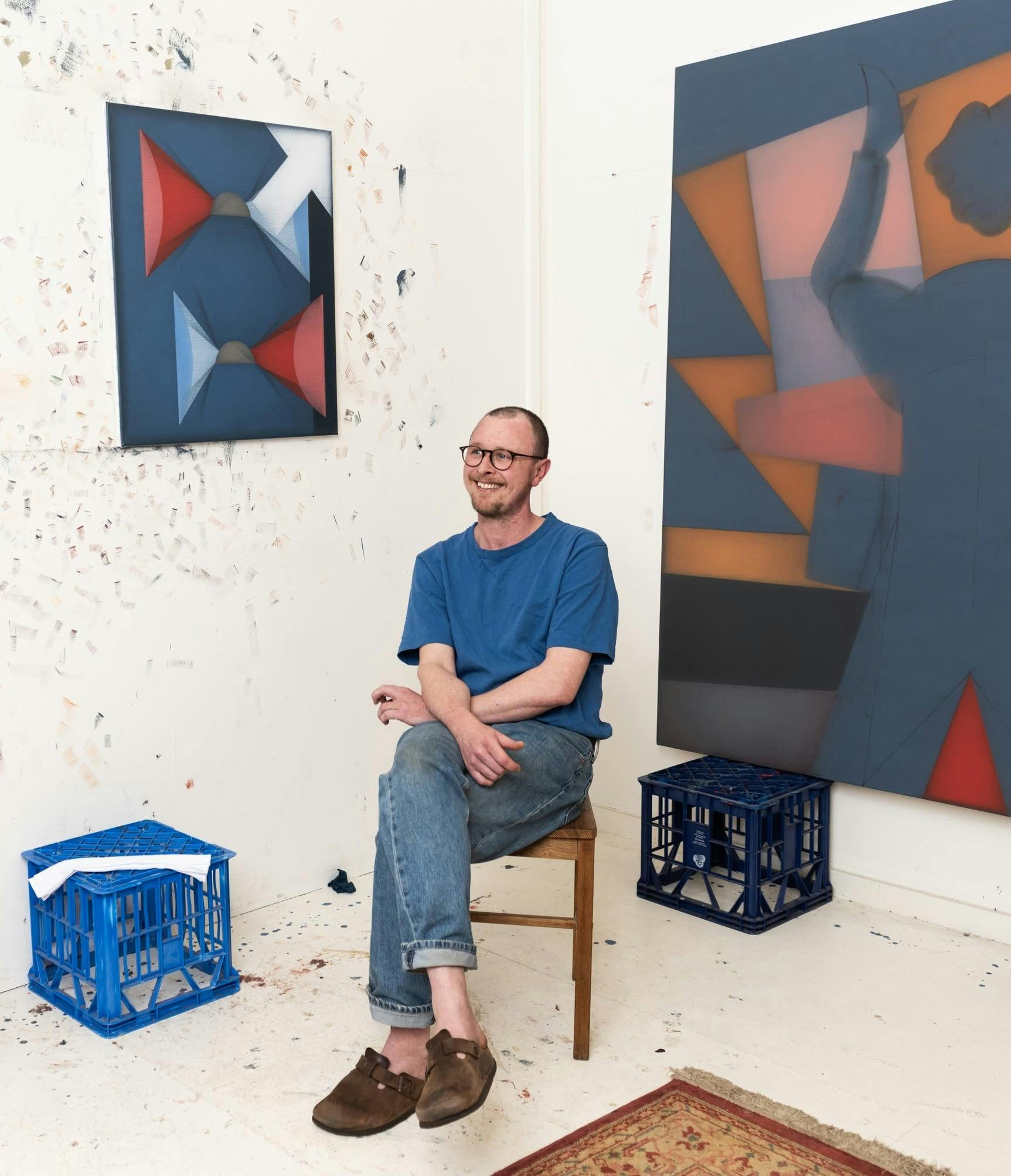 Artist surrounded by paintings.