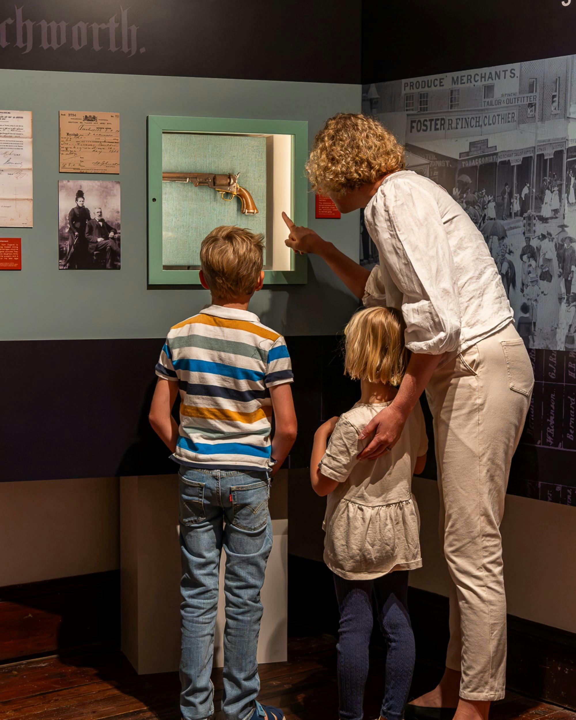 A Mother and two small children peer into a display cabinet