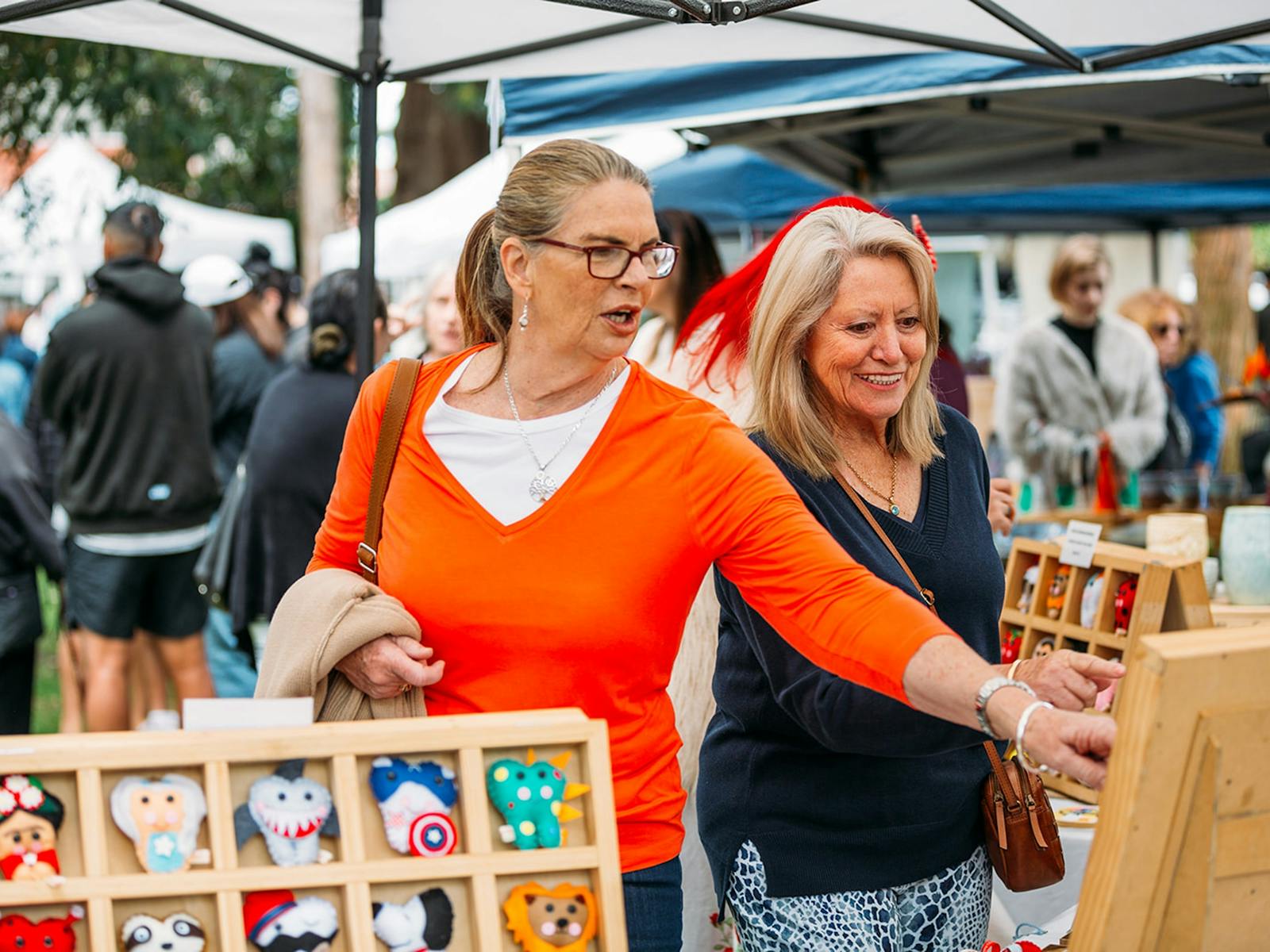 Two women looking at goods at an outdoor stall.