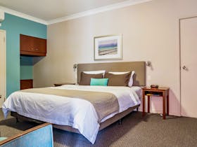 Interior of a deluxe room with a king-sized bed, teal accent wall, and bedside tables.