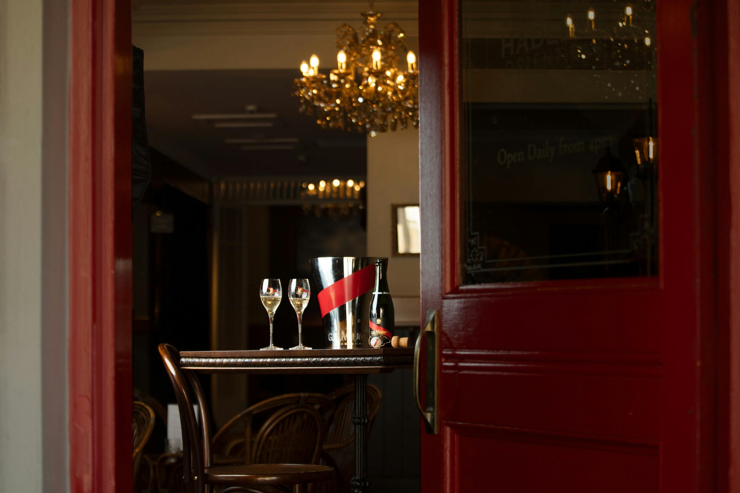 GH Mumm and champagne glasses on a table near the red door to the Orient Bar