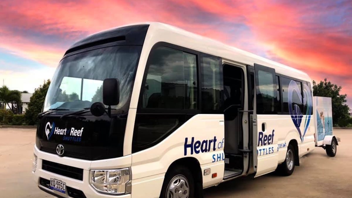 Heart of Reef Shuttles Bus in the depot with a pink sunset sky behind it