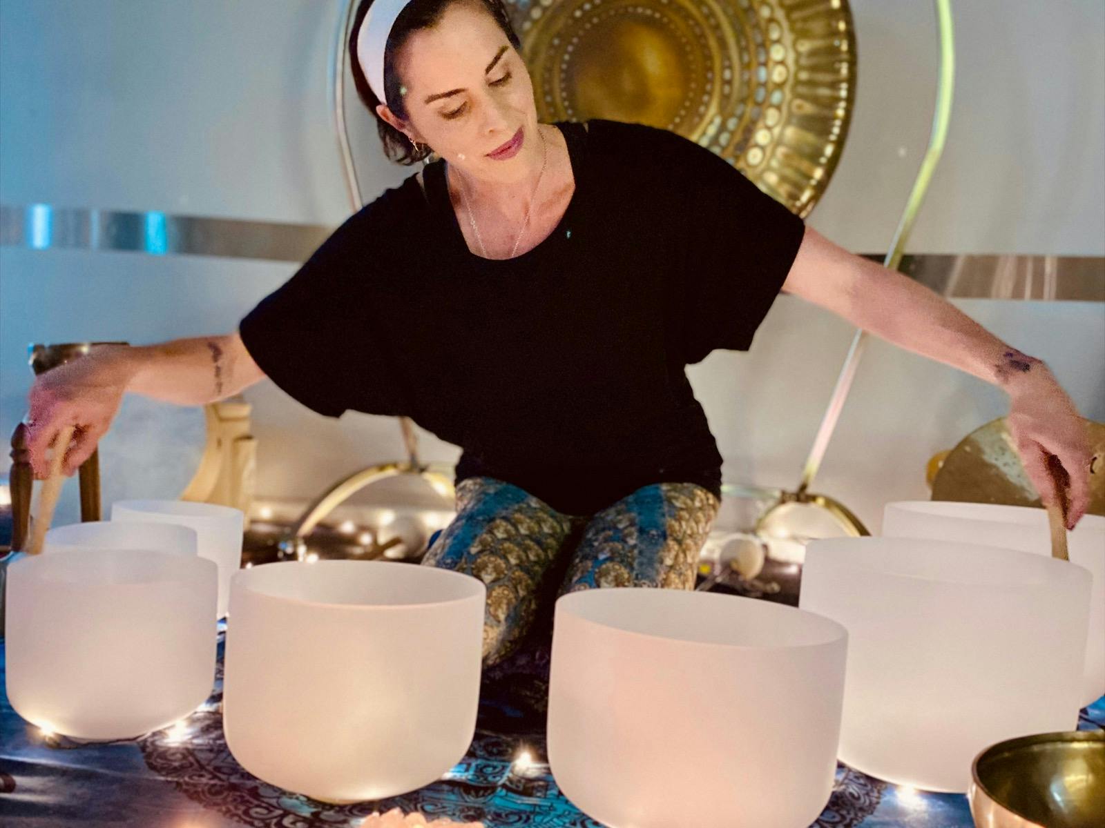 Natalie playing crystal singing bowls, gong in background.