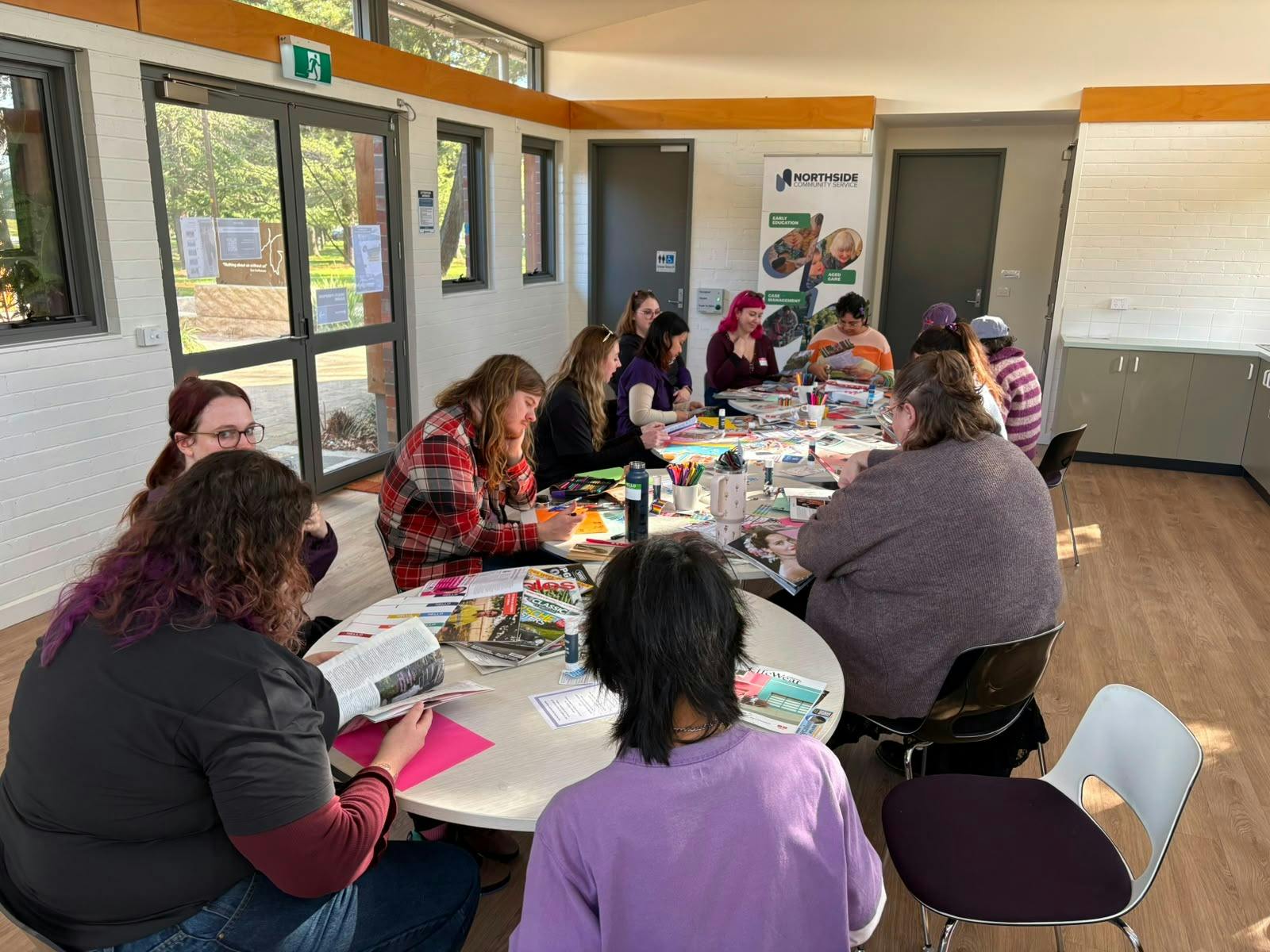 A group of people sitting around tables creating zines