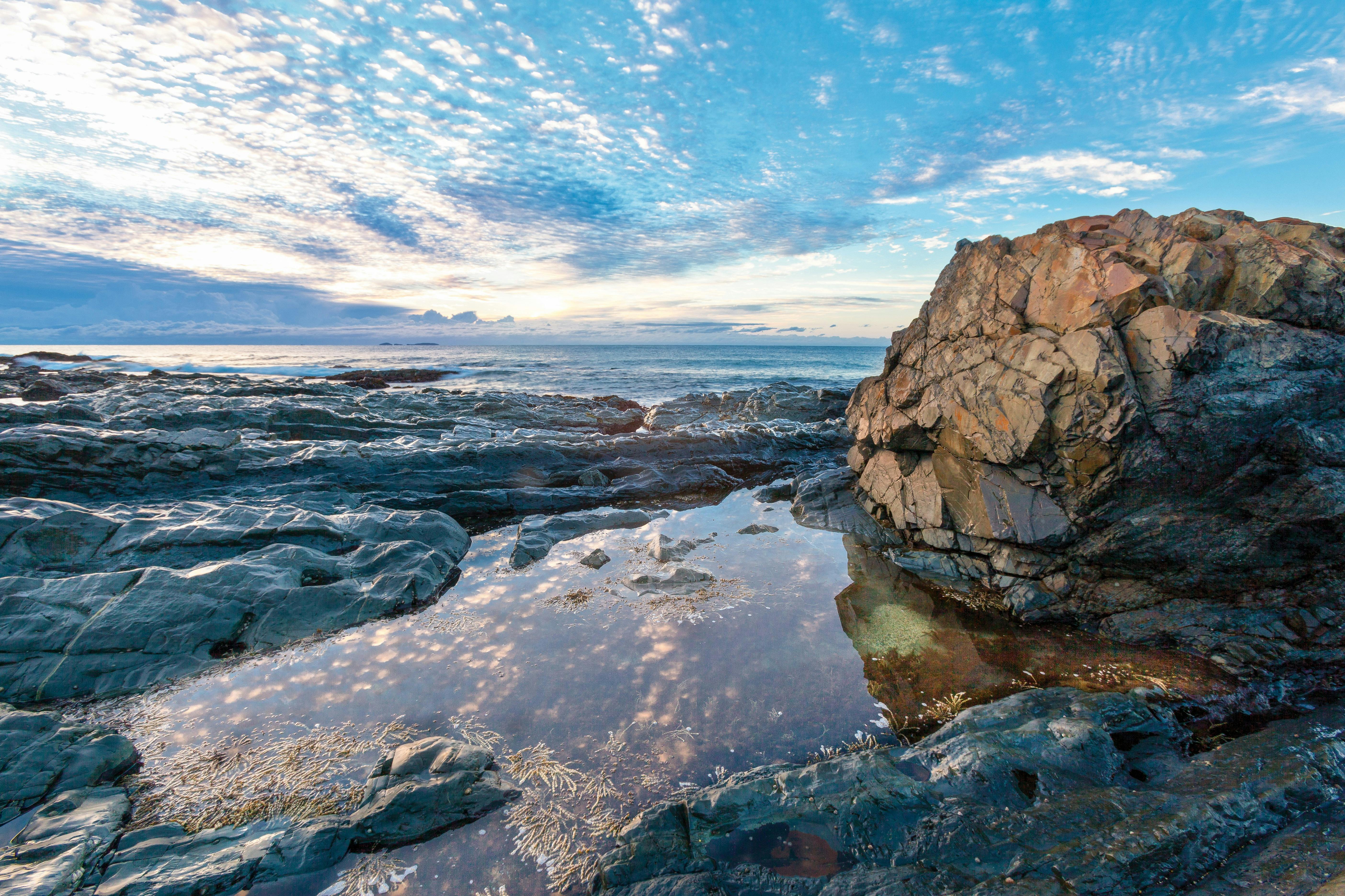 Rock pools and a large rock in the foreground, the ocean and sky in the background