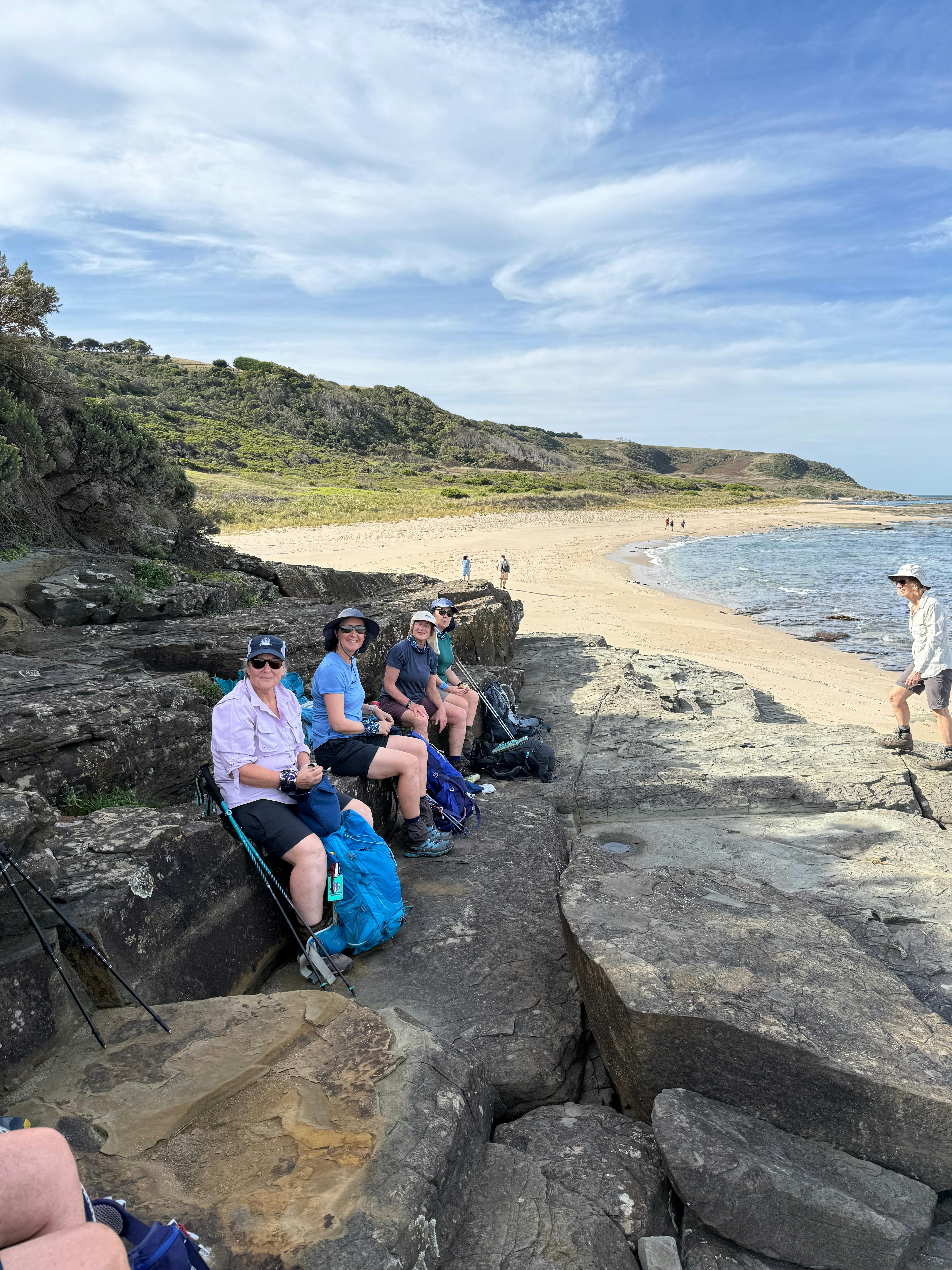 A group of female hikers having lunch on the brqch