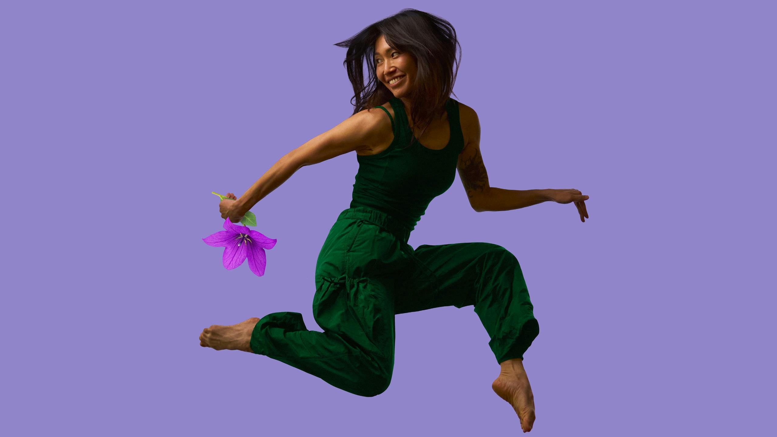 A woman jumping joyfully, holding a flower