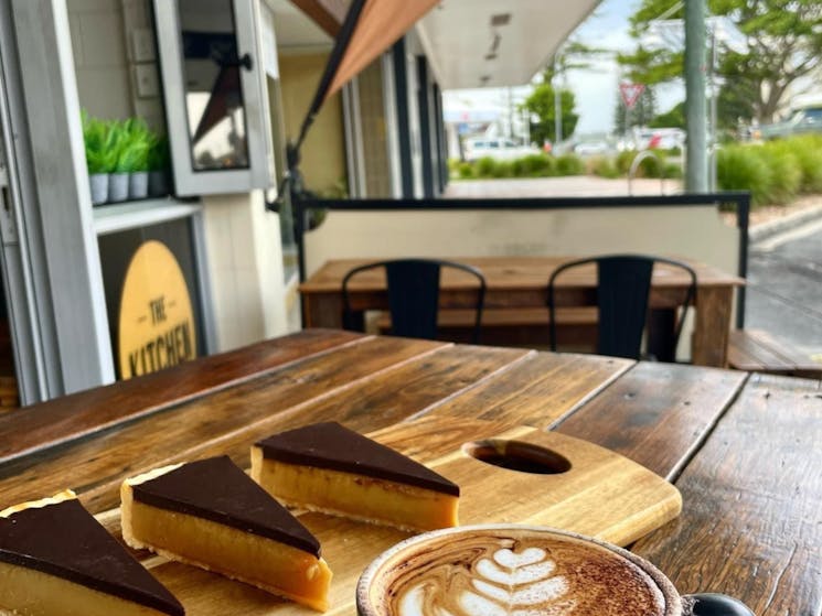 yummy caramel slice and a coffee on an outside timber table