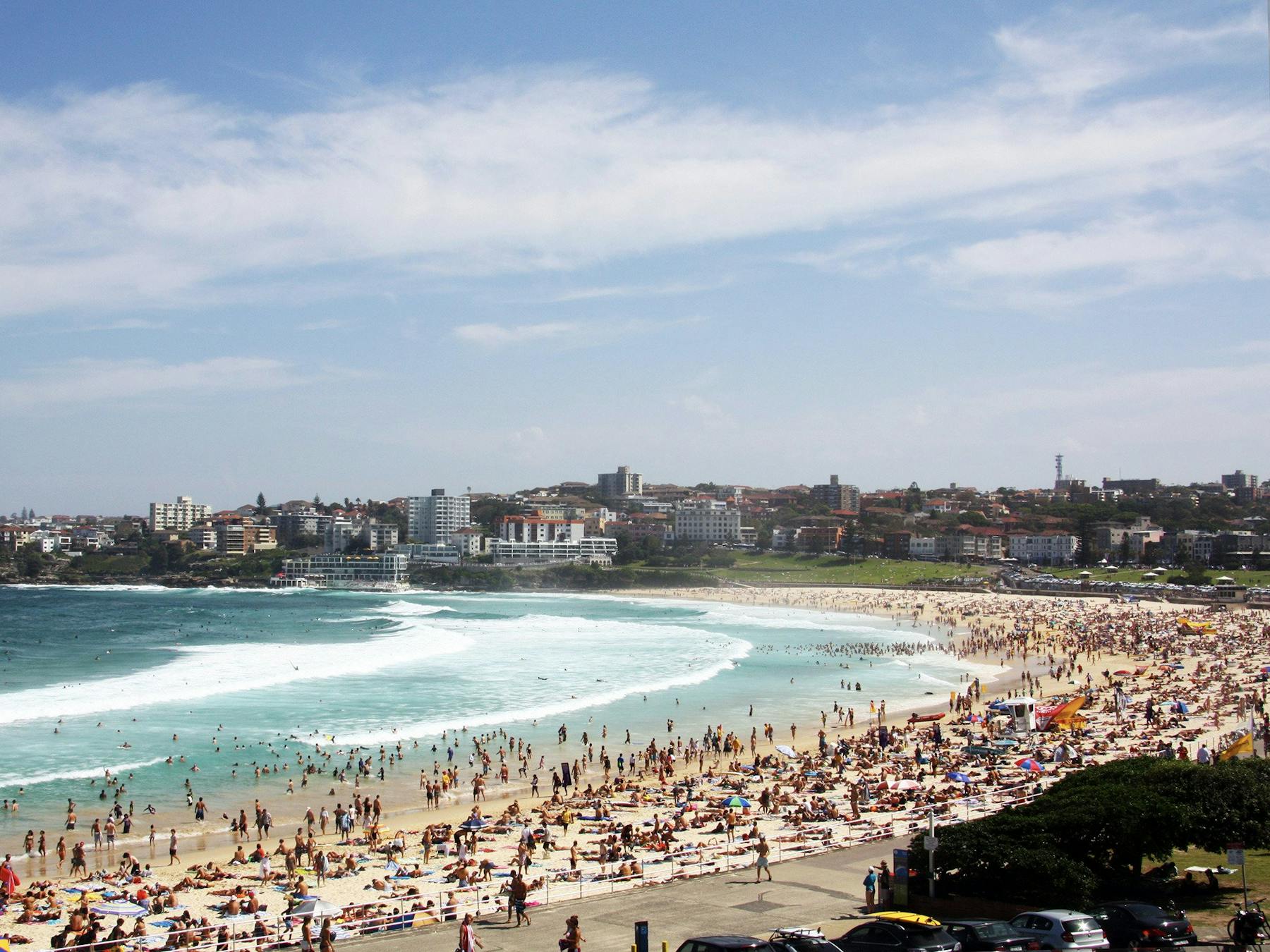 Sweeping view of the famous Bondi Beach with many people spread out on the beach