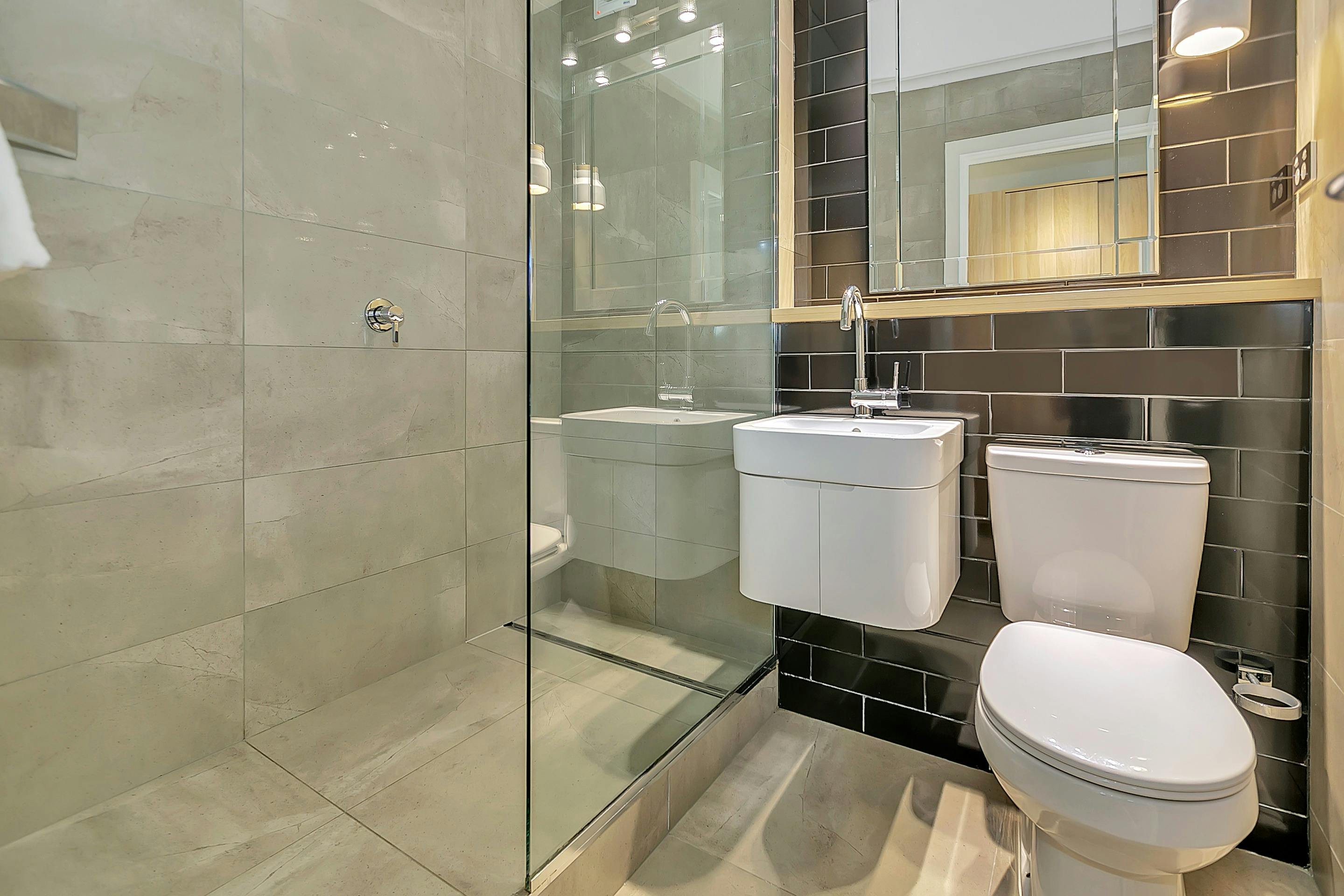 Contemporary bathroom, showing shower, hand basin and mirror, toilet.