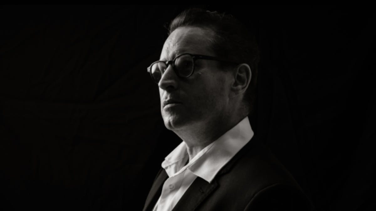 Black-and-white portrait of a timpanist in profile, looking toward the light