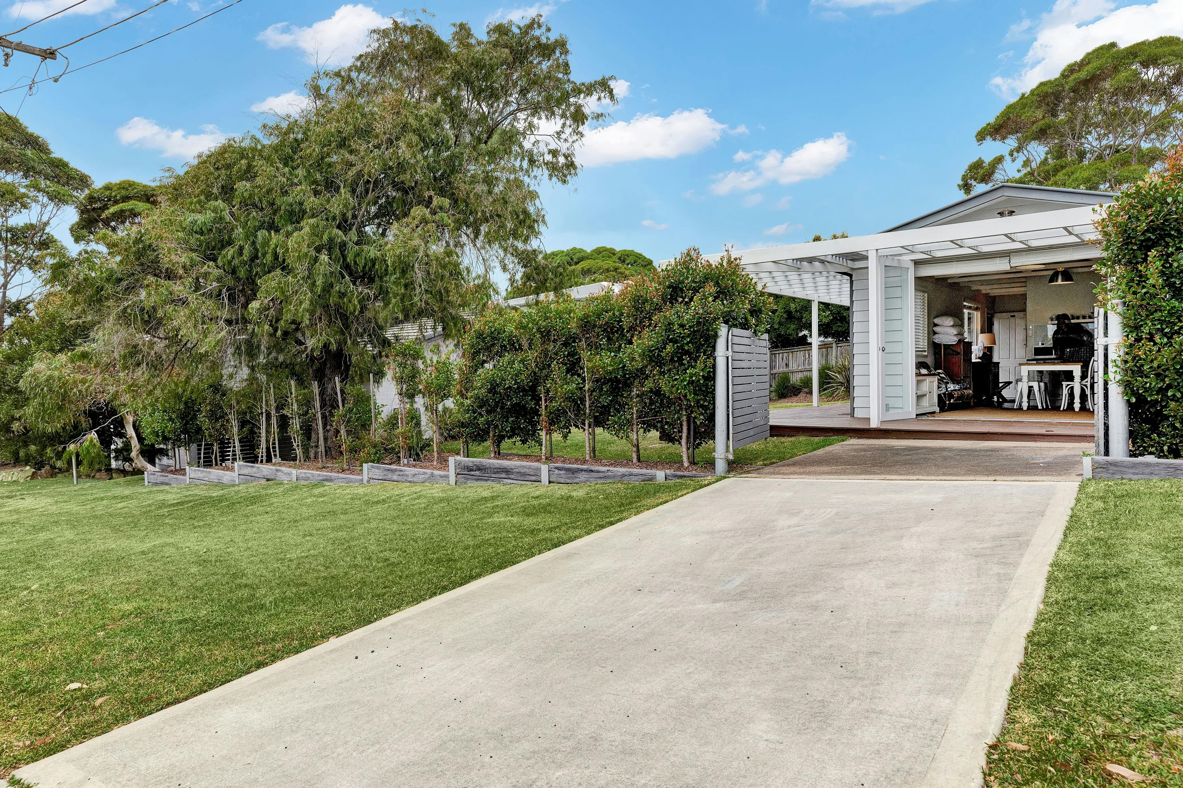 Front of studio with concrete driveway, gate and grassy lawns