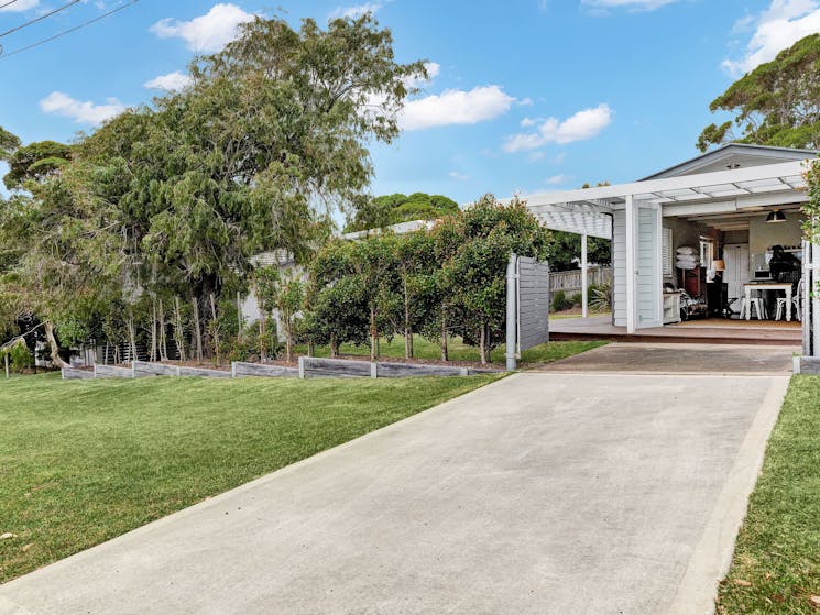 Front of studio with concrete driveway, gate and grassy lawns