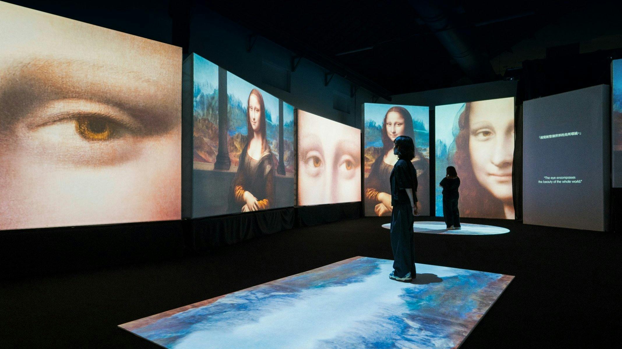Visitors move through a digital gallery surrounded by immersive Mona Lisa projections.