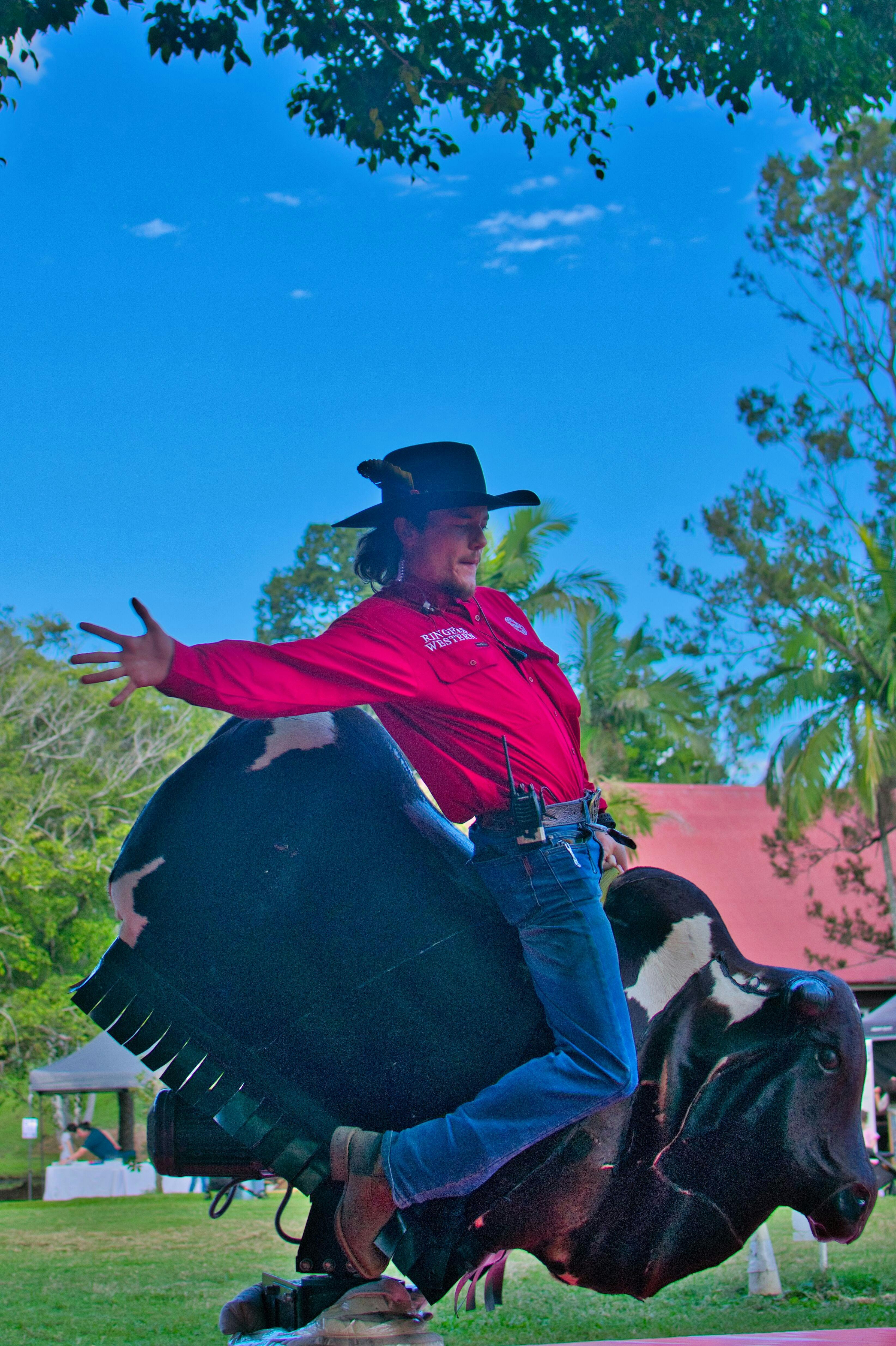Cowboy riding a mechanical bull outdoors at Historic Rivermill.