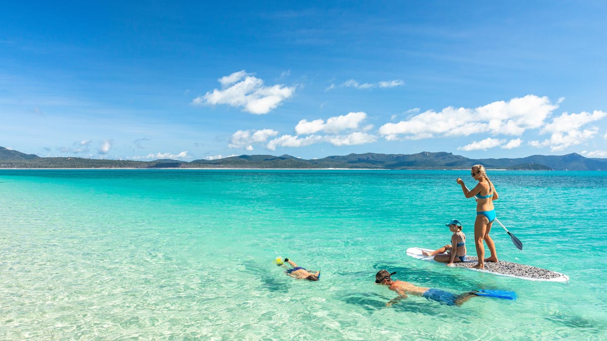 People snorkeling and using a stand up paddle board in the Whitsundays.