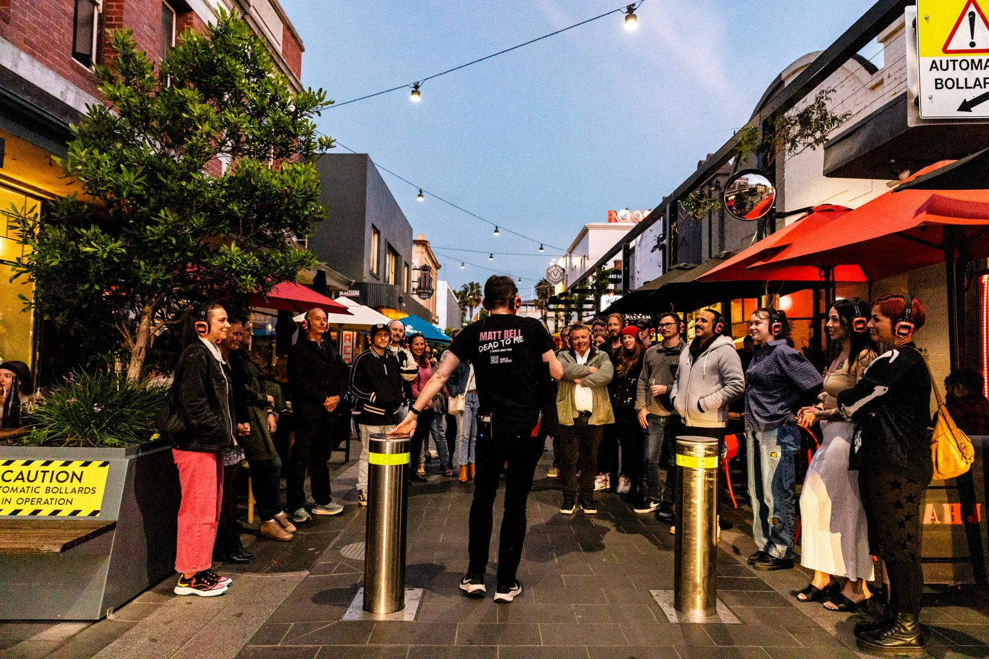 a large group of people outside wearing headphones as a comedian speaks in front of them