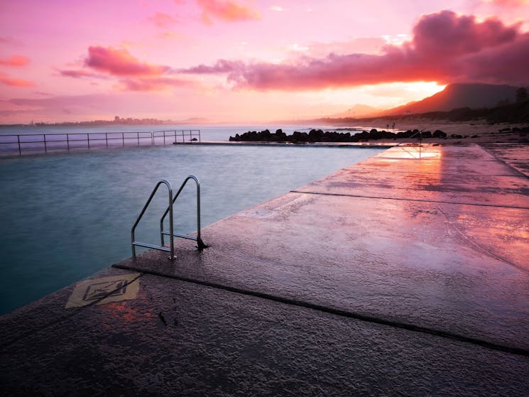 Concrete pool overlooking ocean at sunset