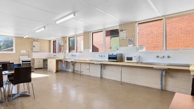 Clean and spacious shared kitchen with oven & cook tops, sink & dining tables for guests to enjoy