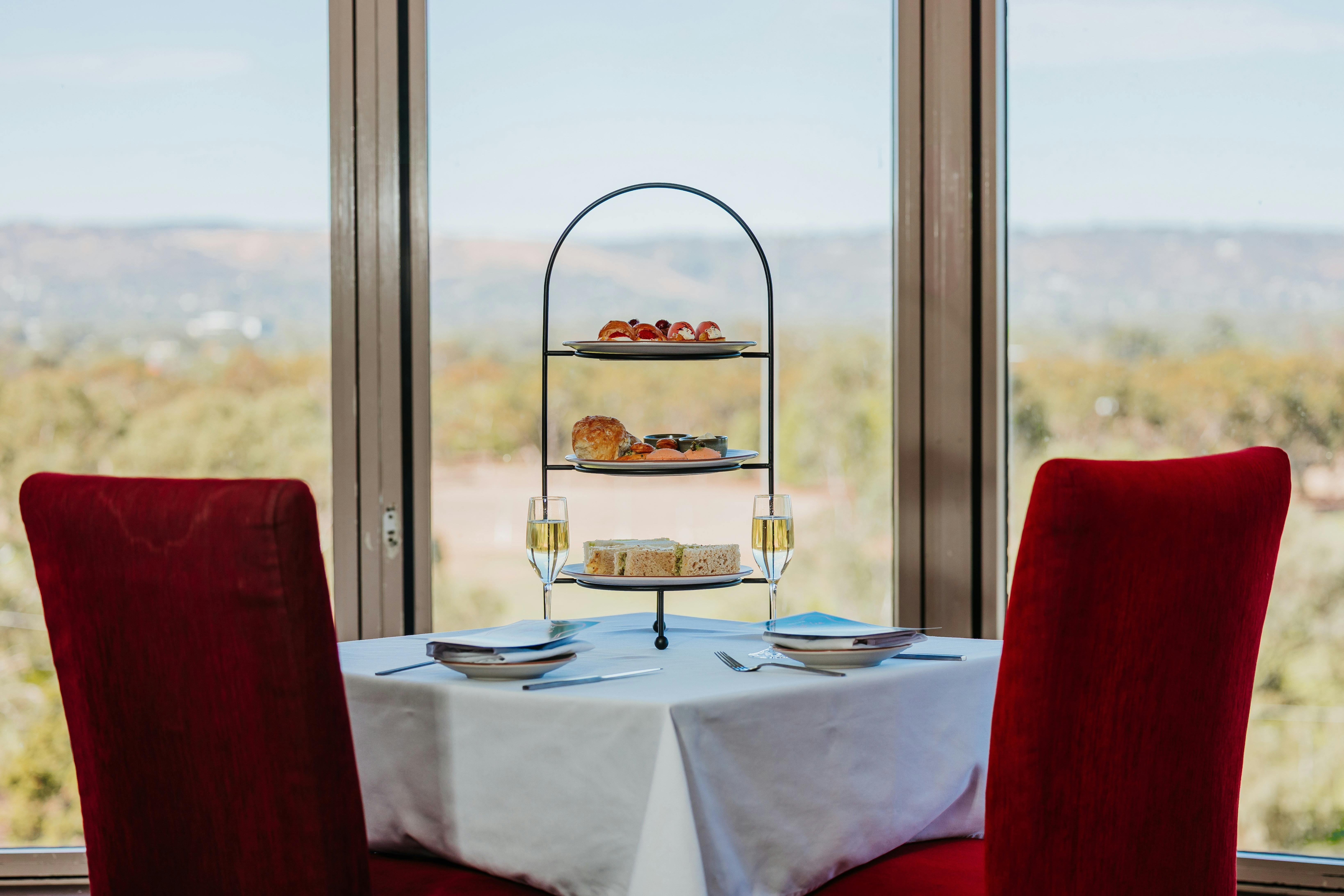 High tea served on a stand with two chairs facing the parklands to show the view