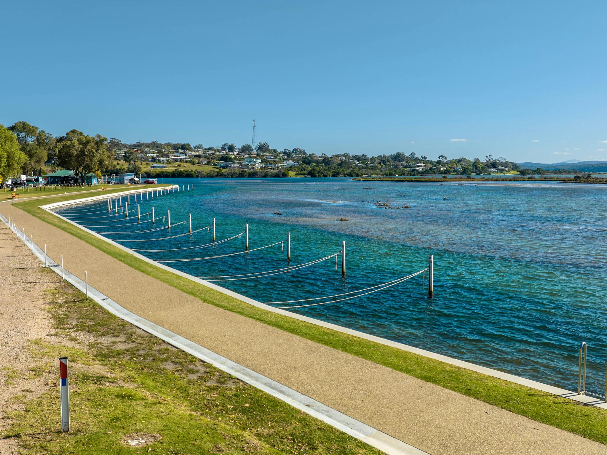 Walking path along the water beside boat moorings and blue water
