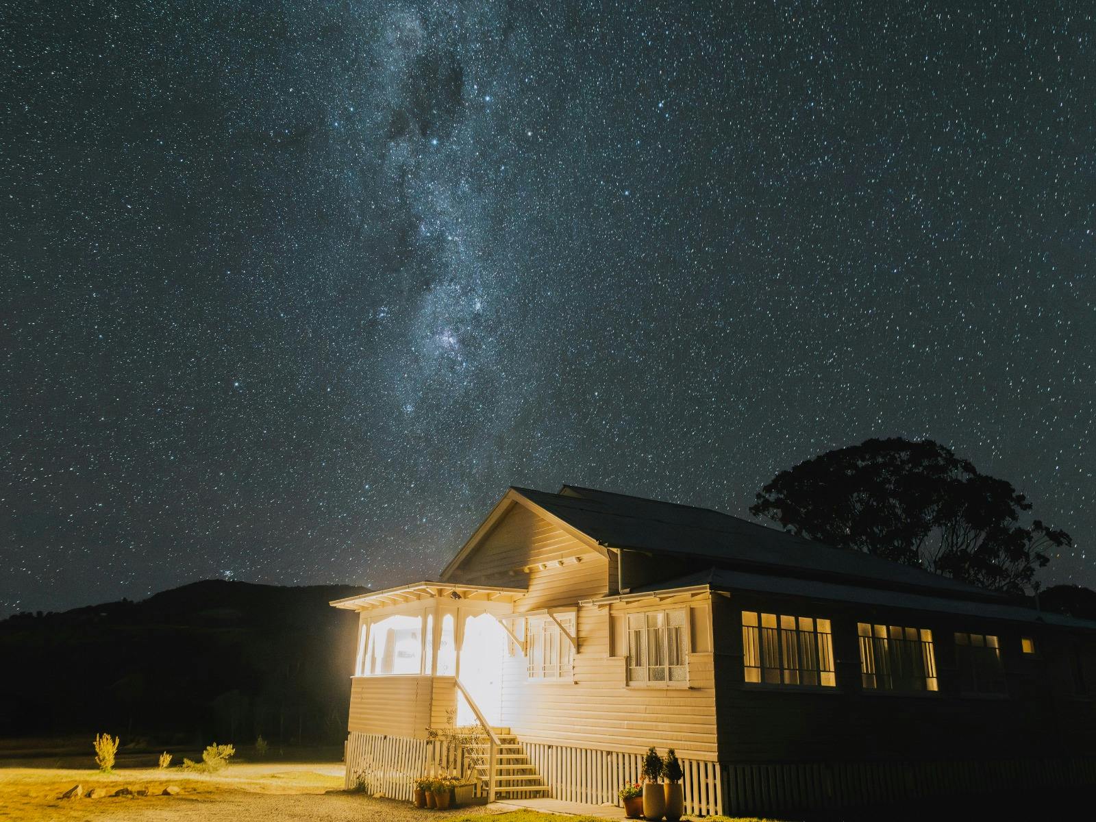 Pink Queenslander building under a starry sky with Mount Mackenzie in the background at night