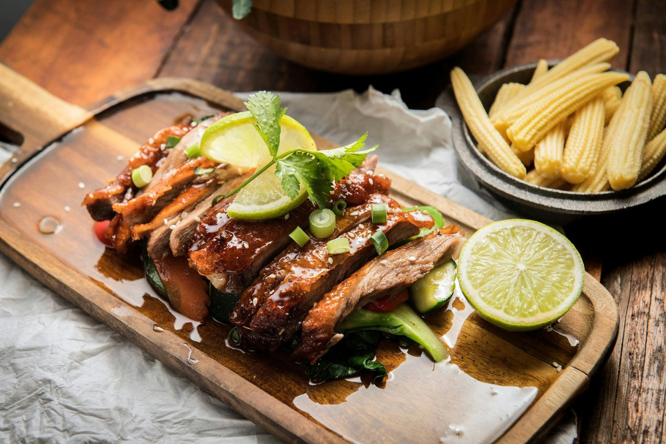 Roast duck on a plate with lime wedges