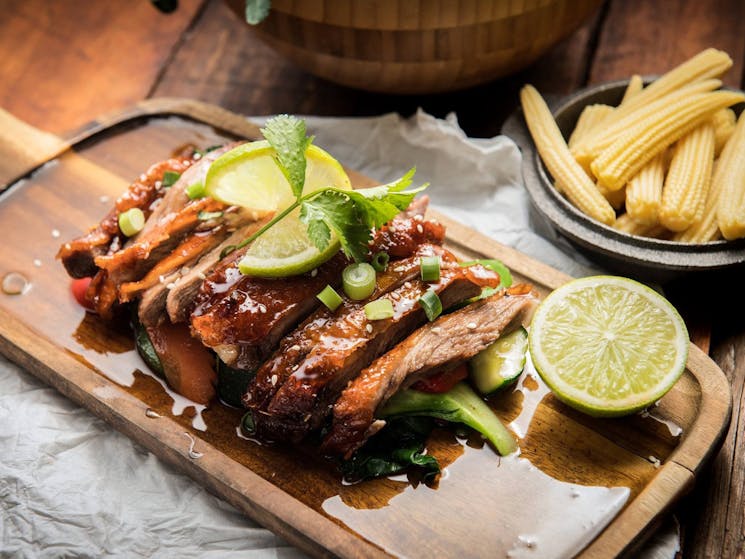 Roast duck on a plate with lime wedges