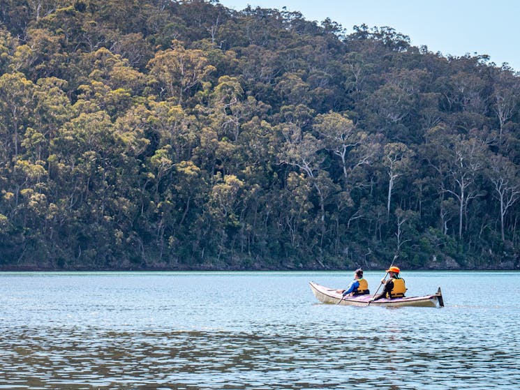 Two guests kayaking in the distance along the Pambula River