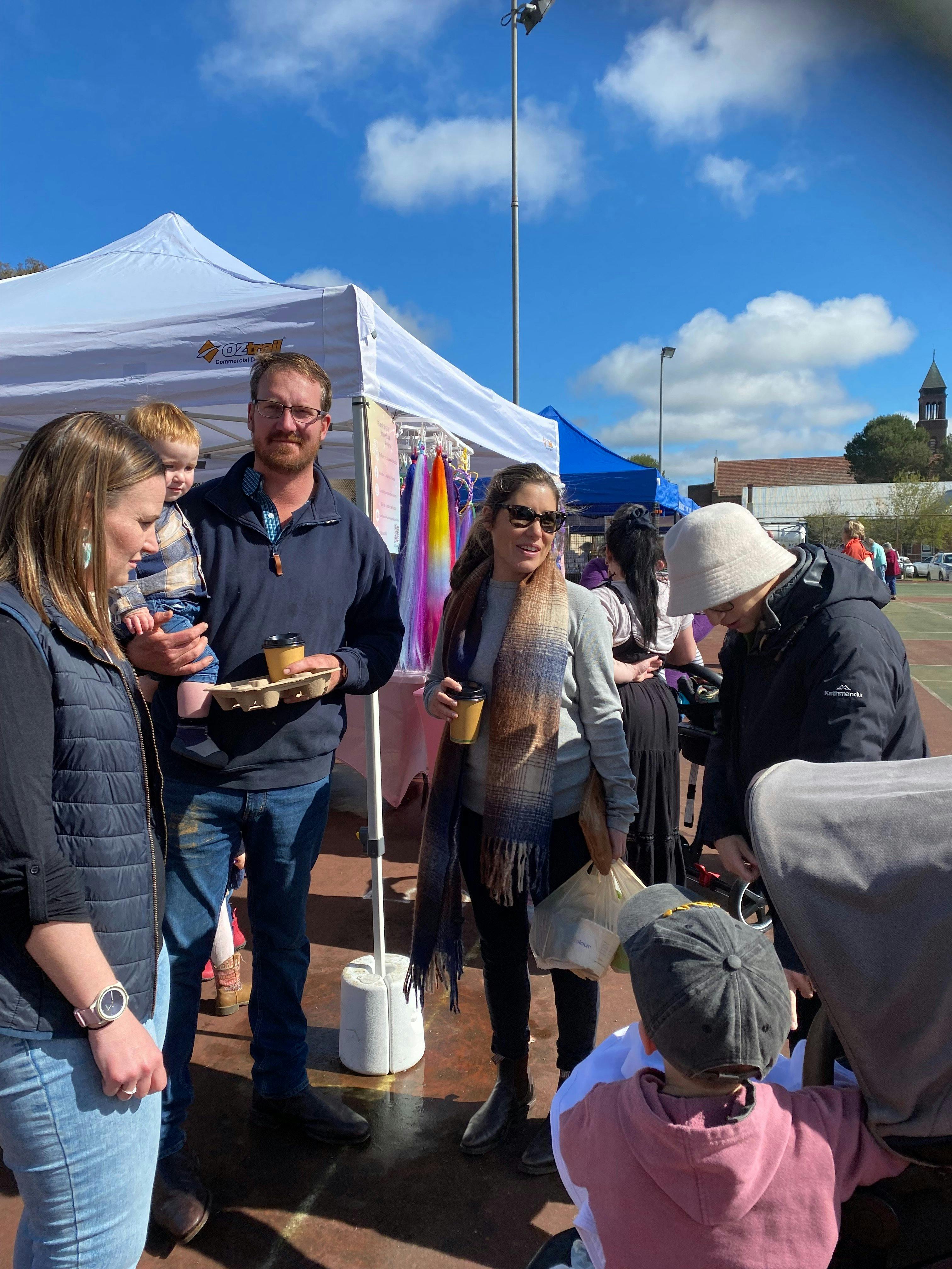 Market-goers gathered with coffee and shopping bags.