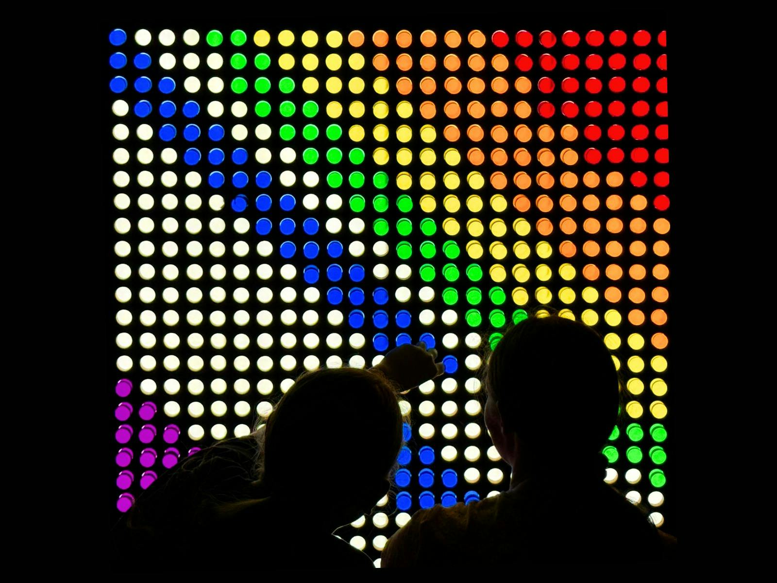A photograph of children creating a colourful design on a large lightbox A photograph of children creating a colourful design on a large lightbox