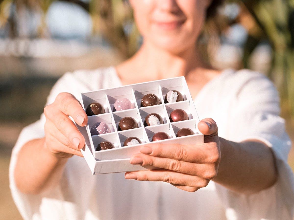 Woman holding an open box of chocolates in front of her Woman holding an open box of chocolates in front of her