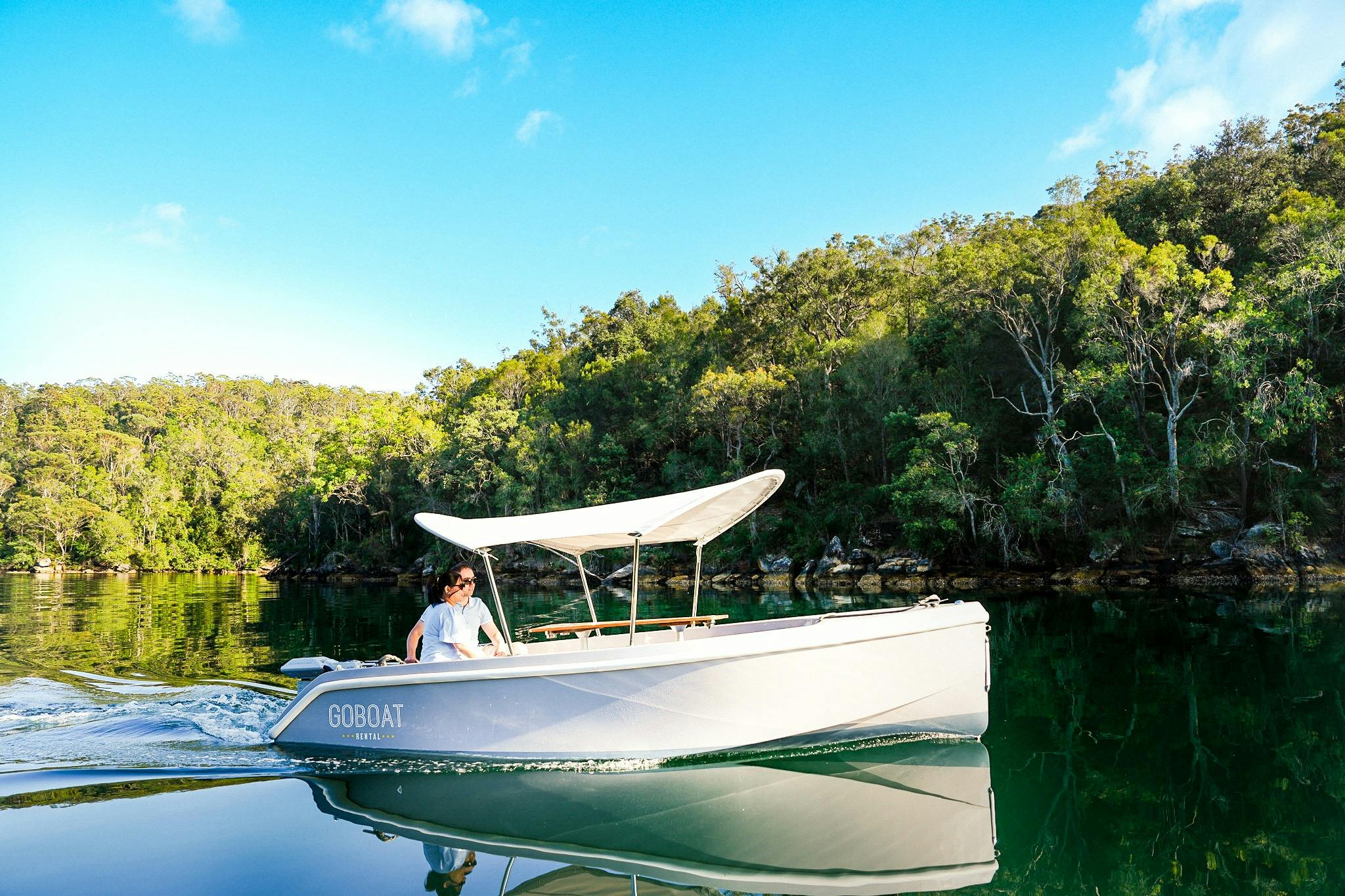 Person enjoying a GoBoat ride on calm waters at Akuna Bay, Ku-ring-gai Chase National Park.