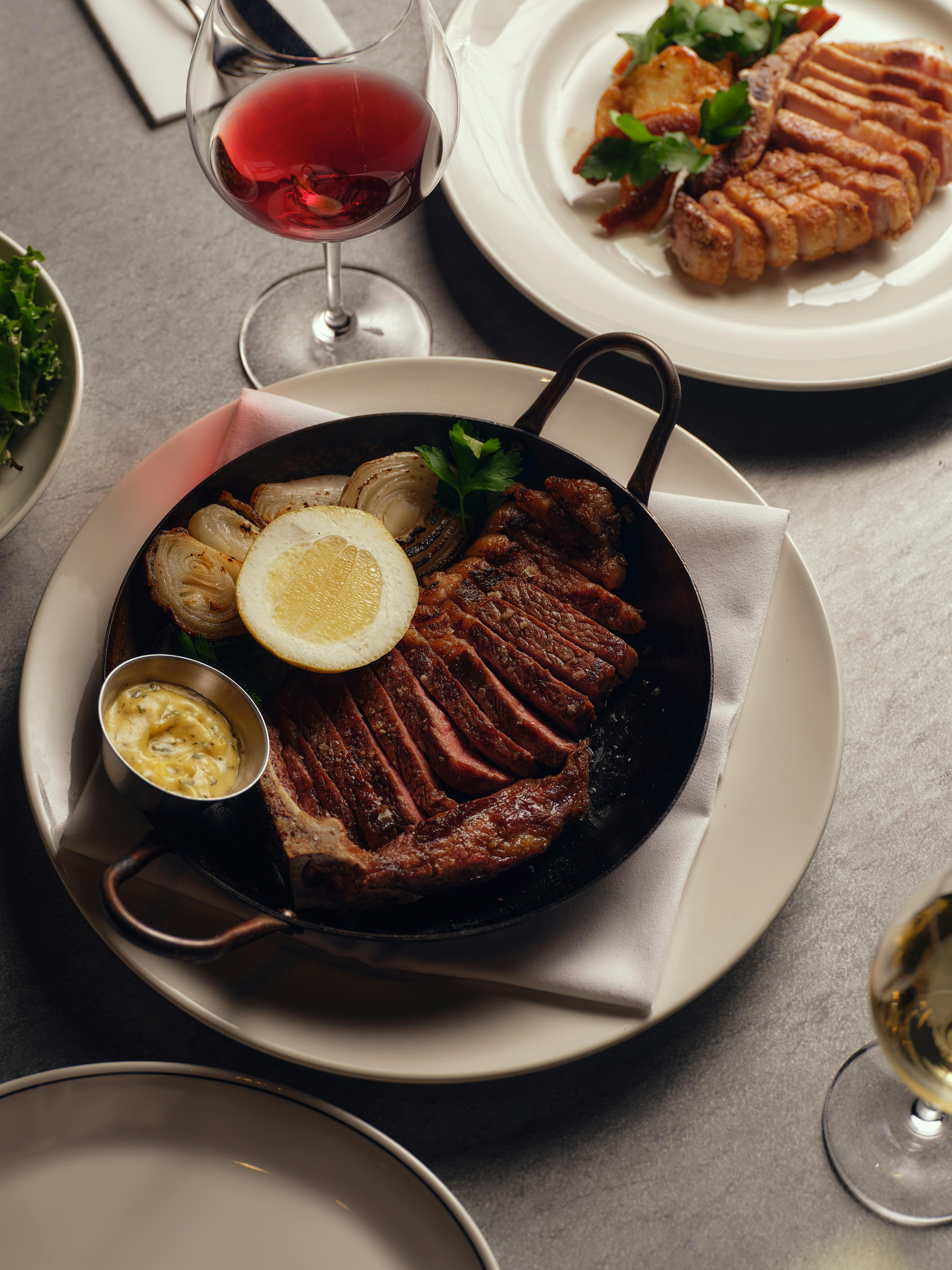 A plate of sliced steak, mustard, lemon and onions