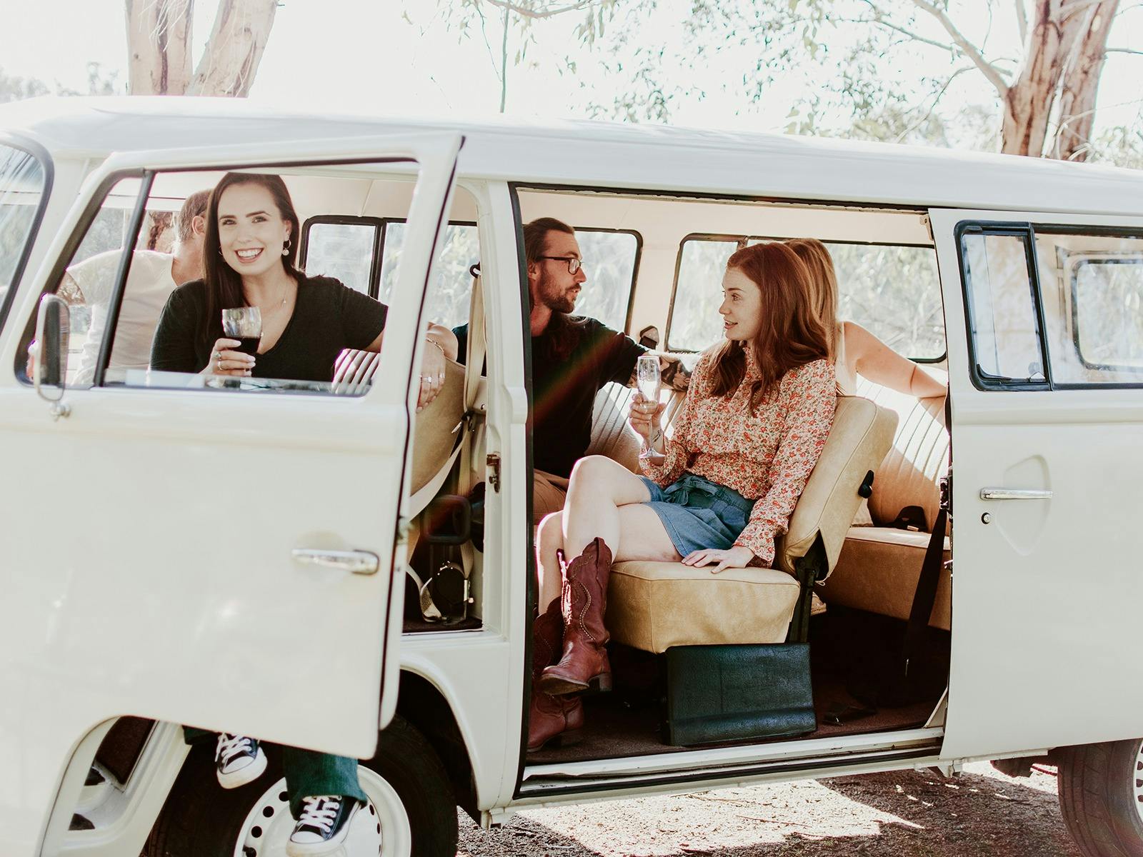 Friends seated comfortably in the kombi with a glass of wine
