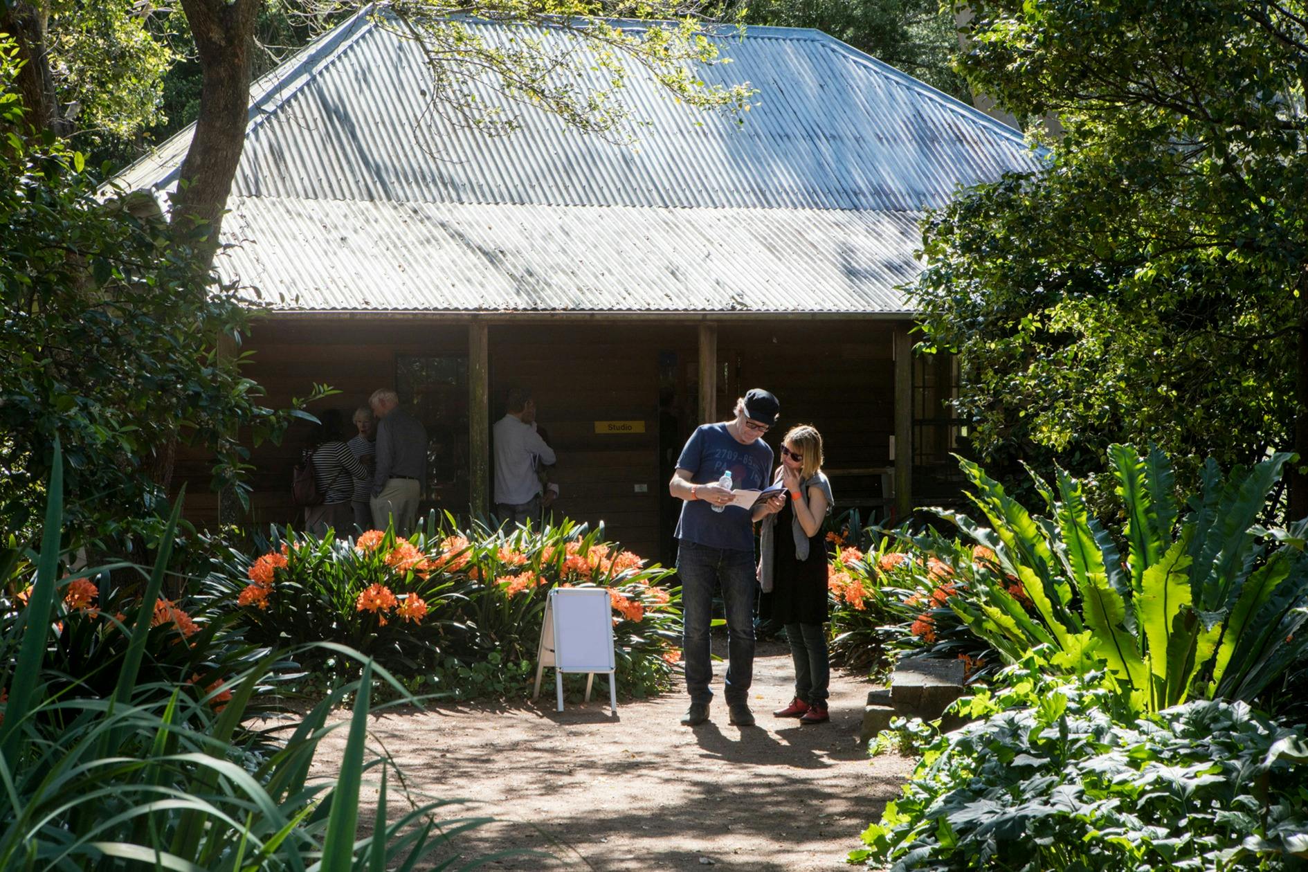 Two people stand outside a cottage building