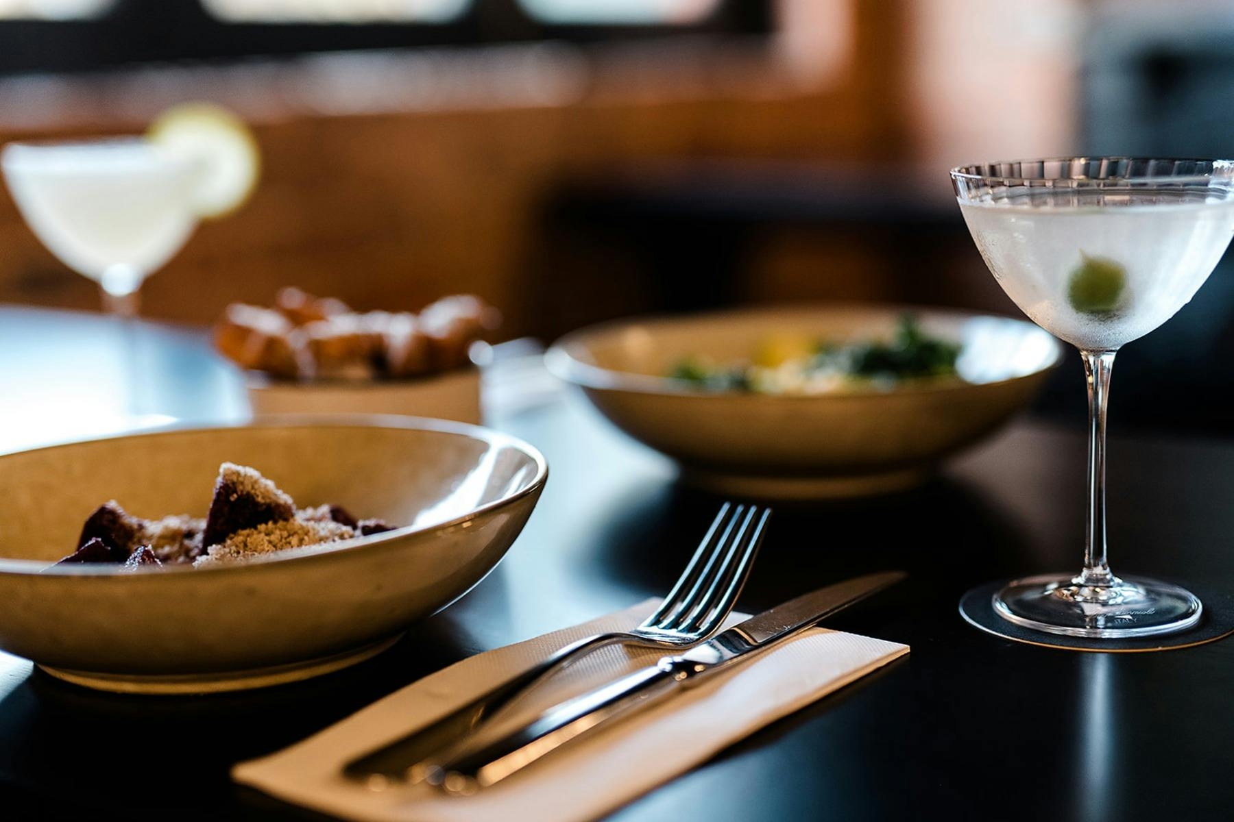 Plates of food served with a martini on a black tabletop