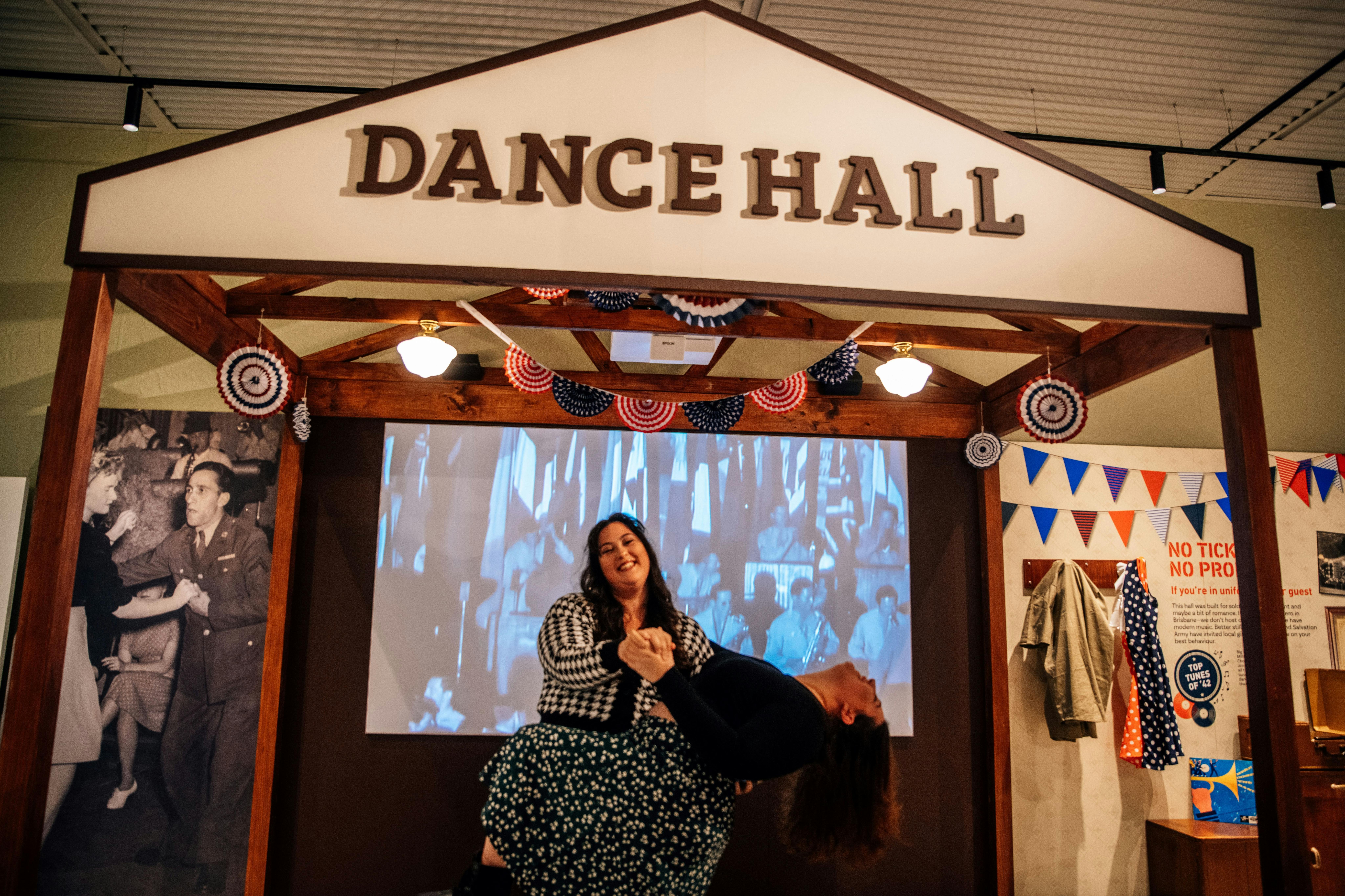 Two ladies dancing inside a small dance hall display inside the interactive exhibit