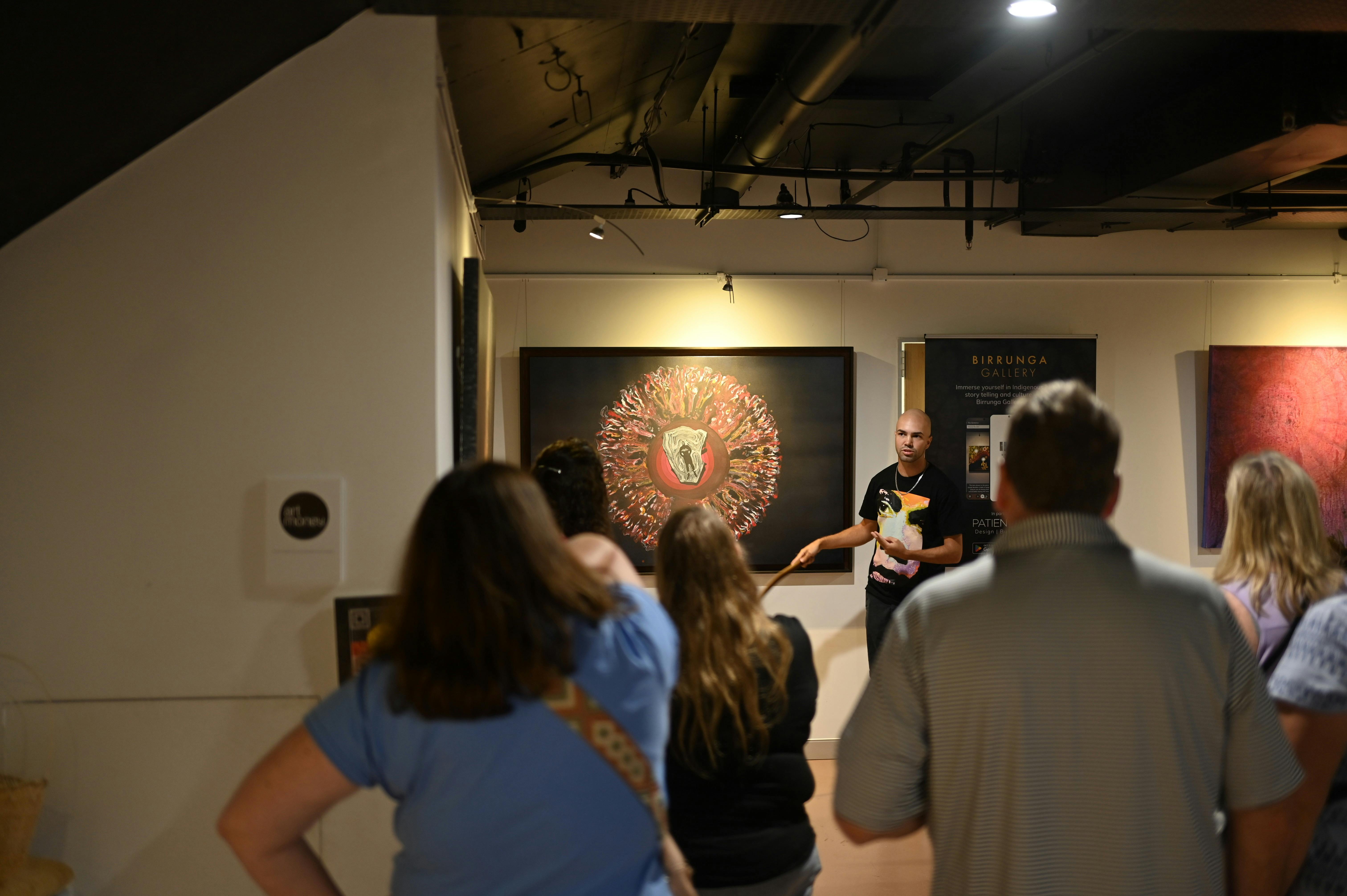 Kane Gestures at artwork with group