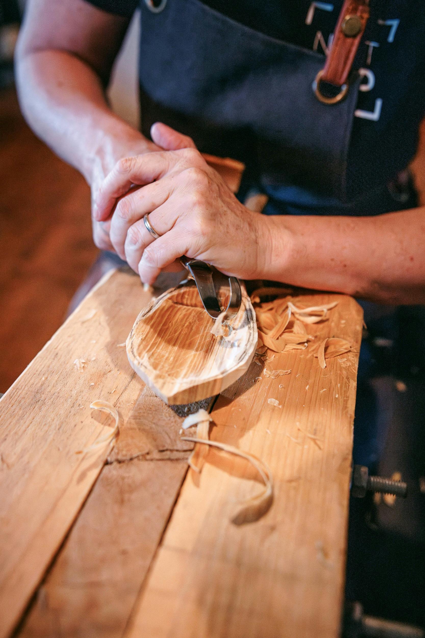 close up of hand carving a wooden spoon
