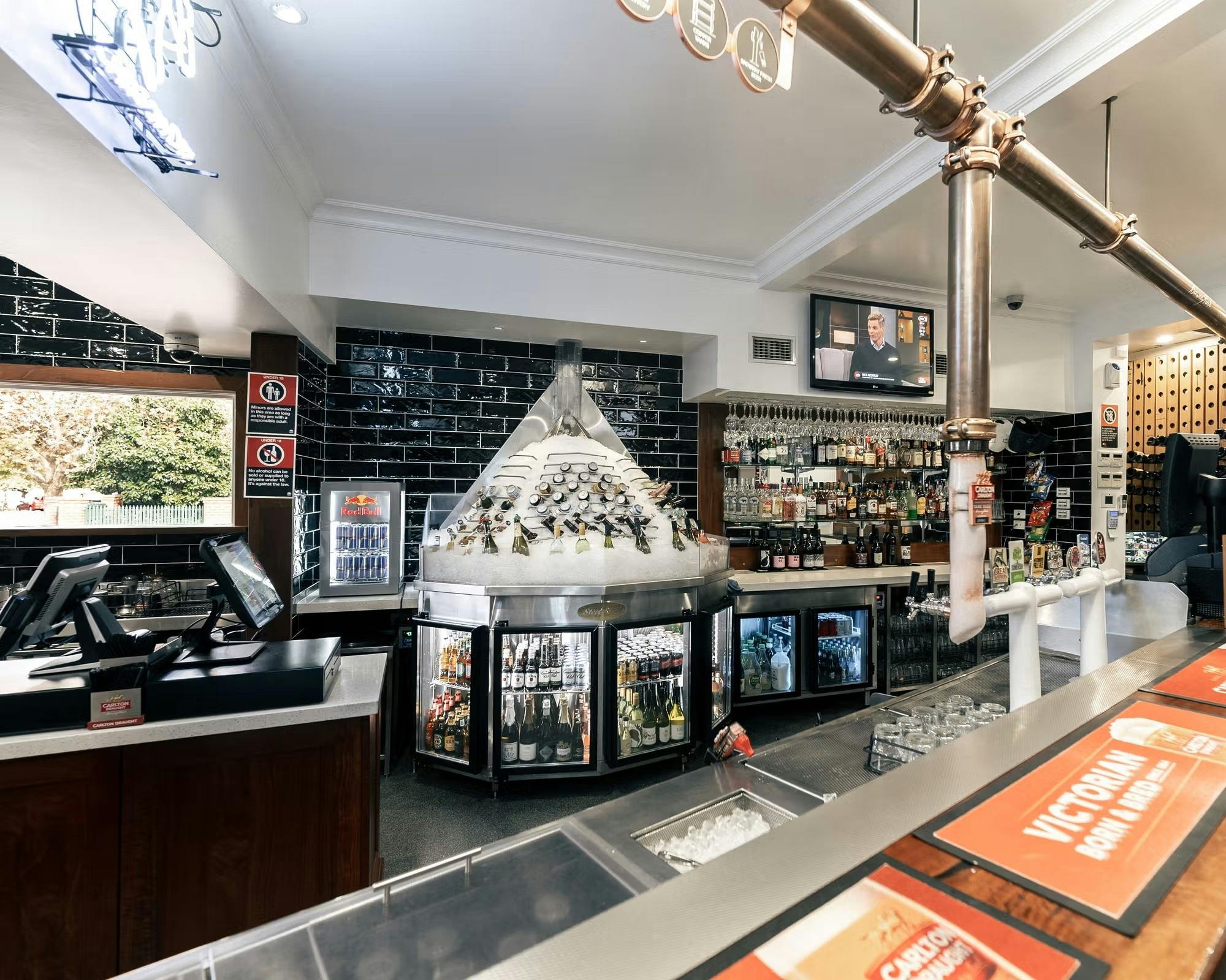 An indoor bar with an ice machine stacked with cans and bottles