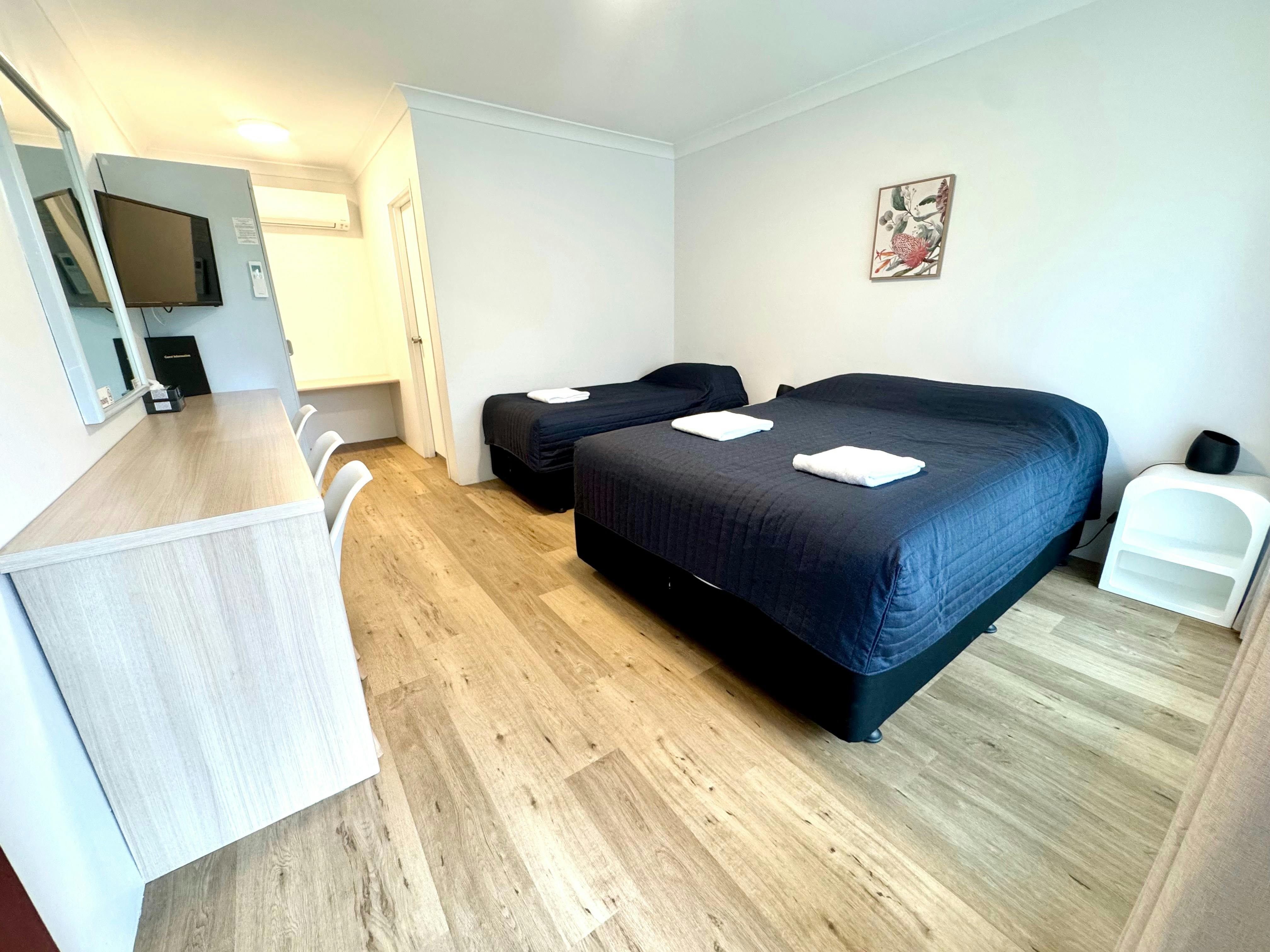 Sutherland Motel Twin or Triple Room, queen plus single bed, bedside tables, lamp, television, desk