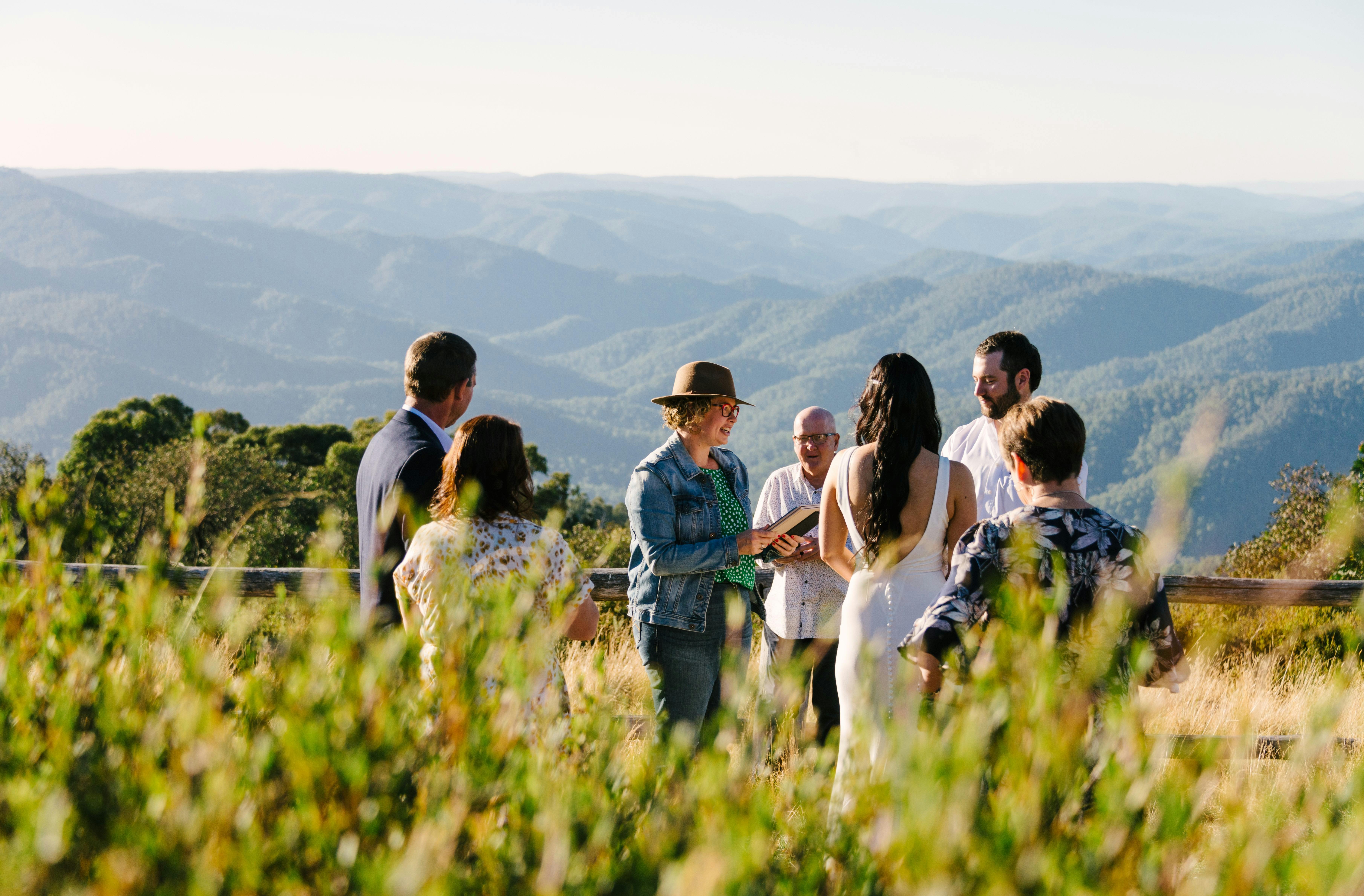 Bride and groom with their parents during the wedding ceremony, with mountains in the background.