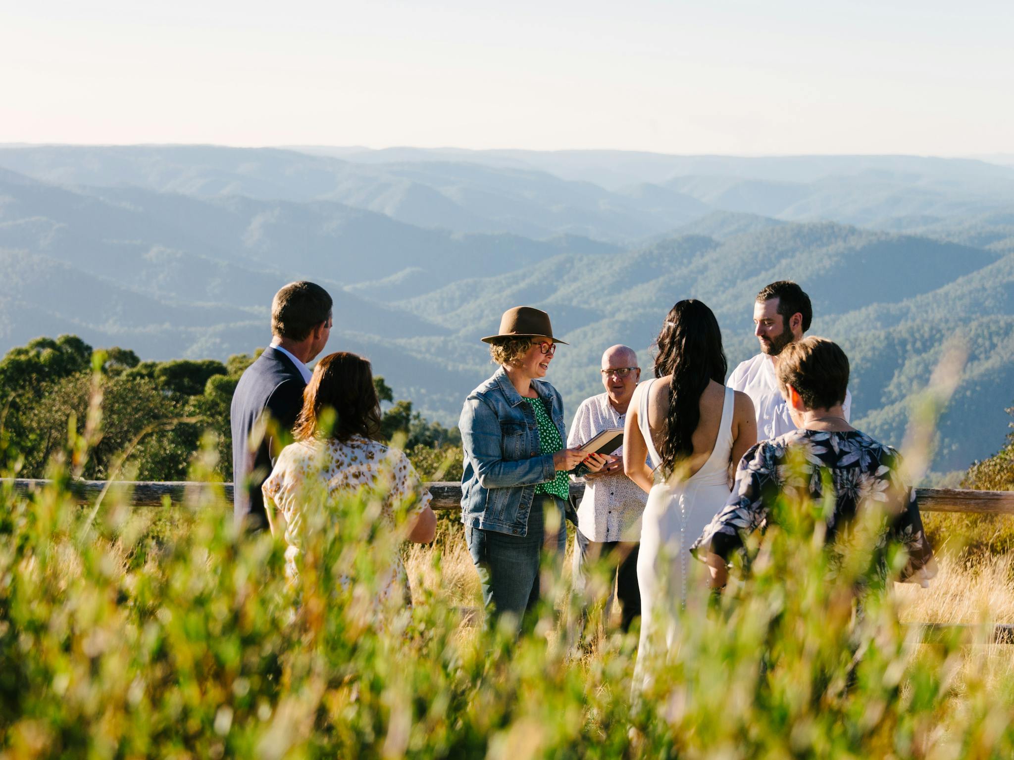 Bride and groom with their parents during the wedding ceremony, with mountains in the background.
