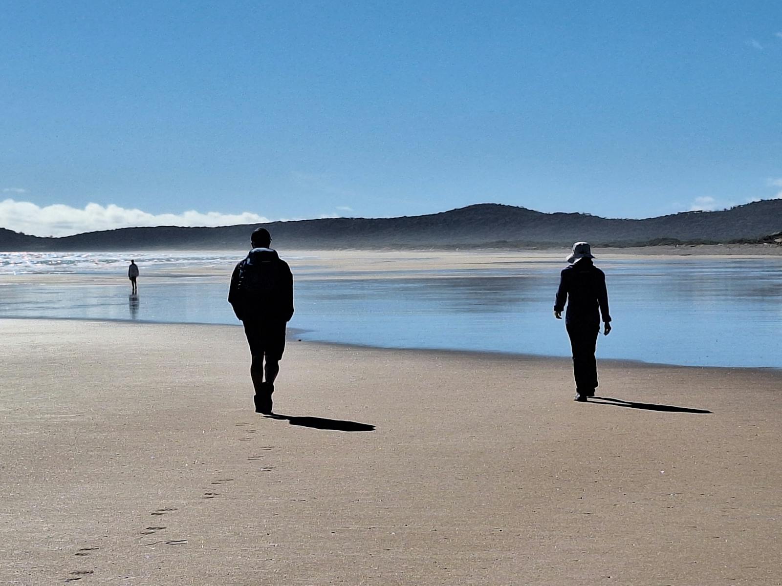 Two people walking on beach  withe mountain silohuette in background